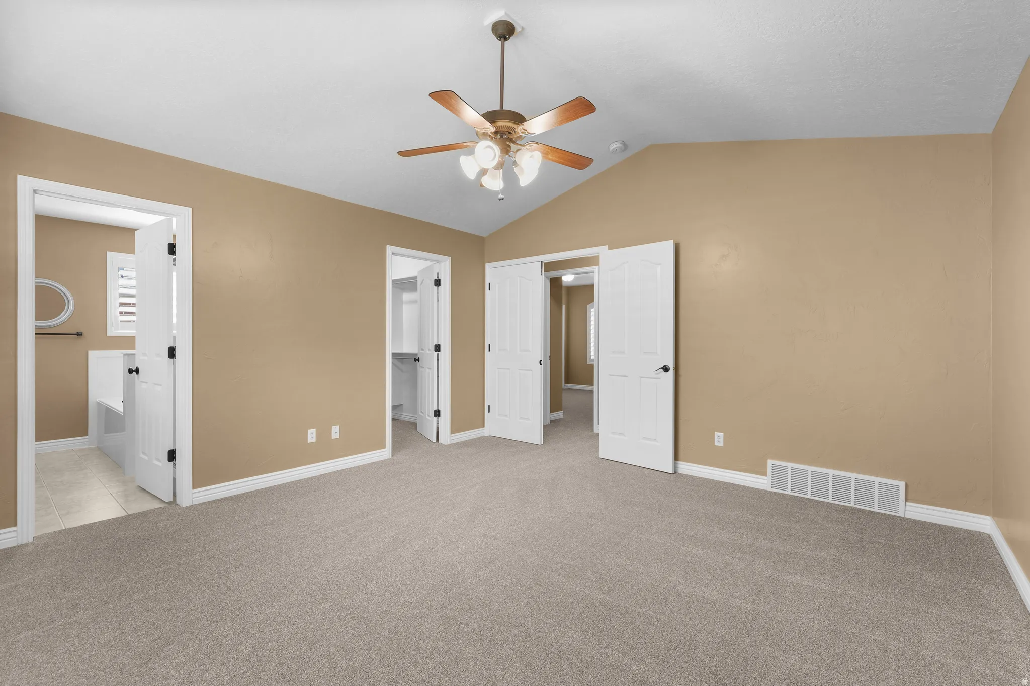 Spacious room featuring vaulted ceilings, light wall paint, and gray carpeting