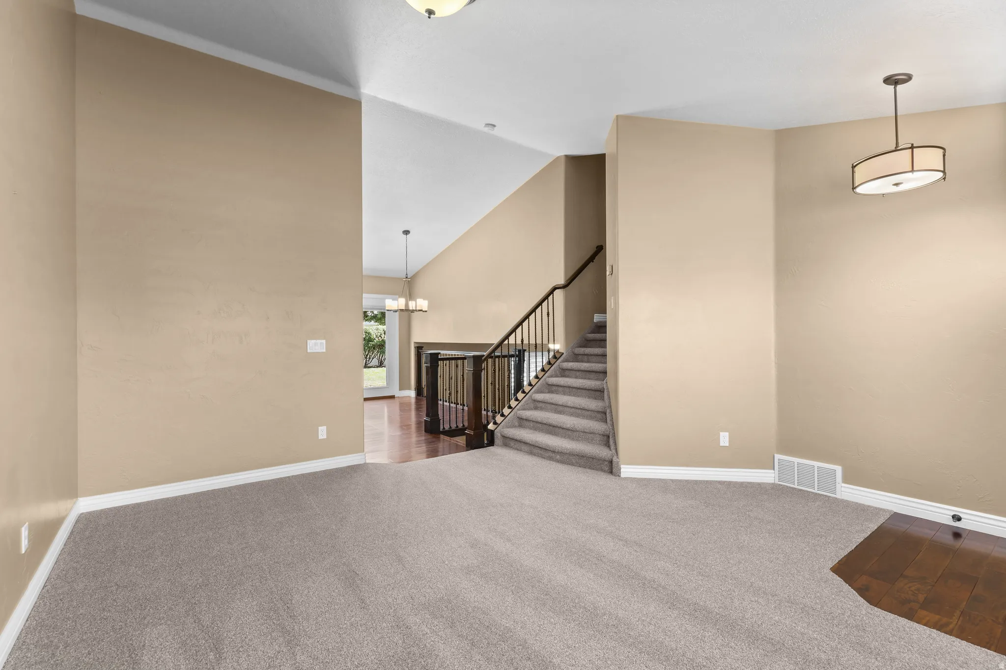 Spacious interior featuring vaulted ceilings and a blend of carpet and wood-finish flooring