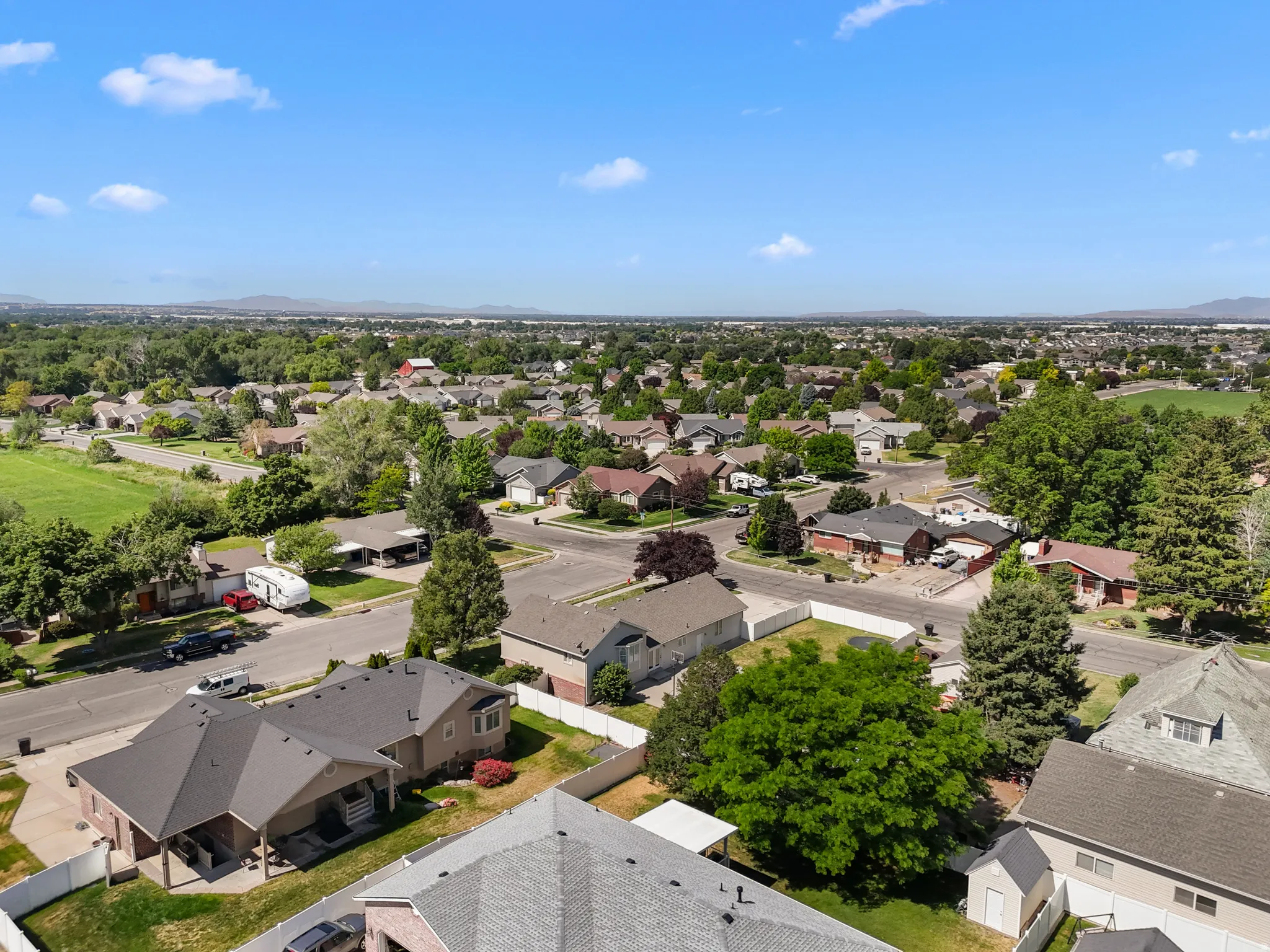 Suburban neighborhood featuring mature landscaping, a mix of residential roof styles, and distant mountain scenery