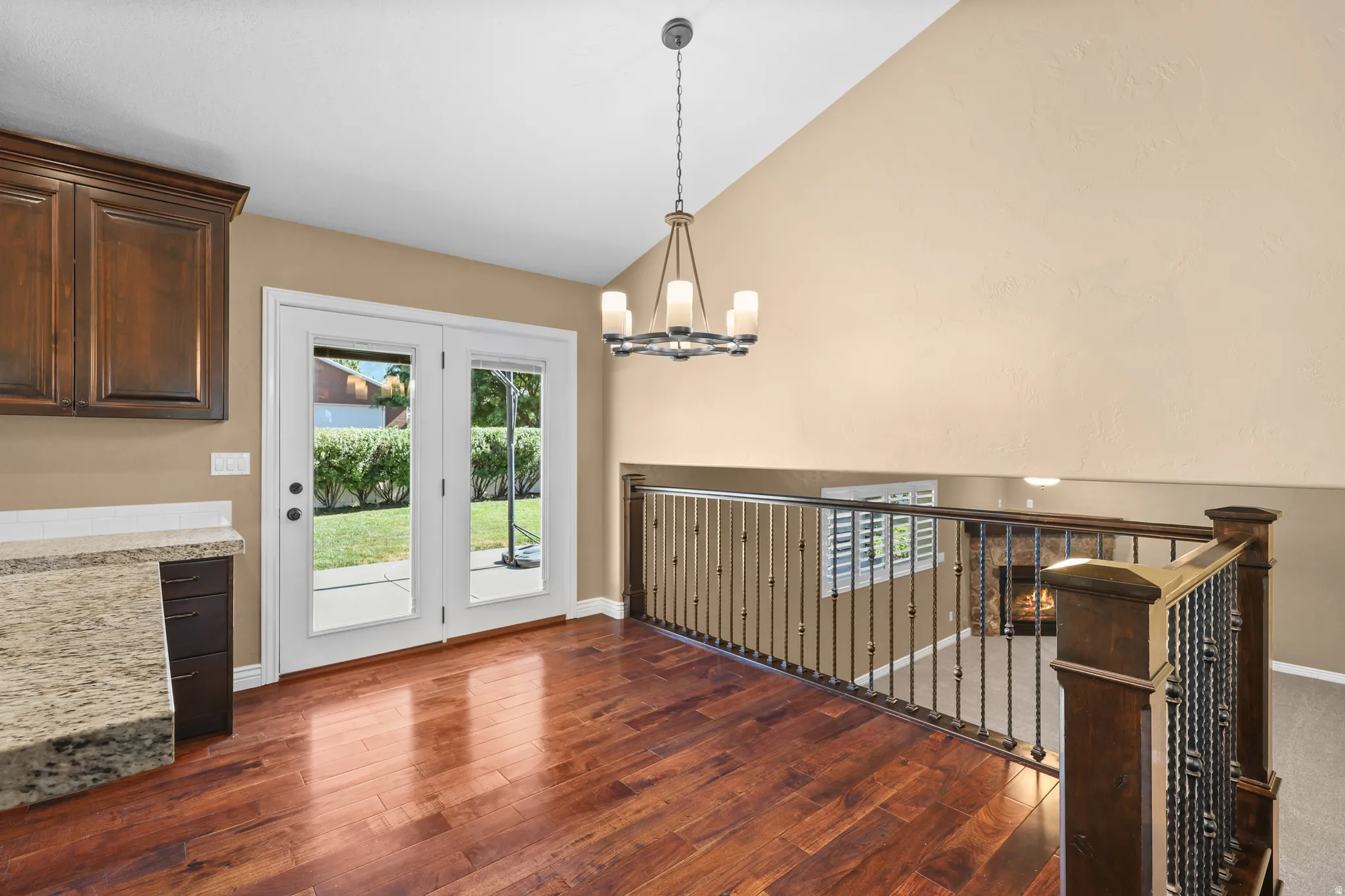 Open concept dining area featuring wood-finish flooring, a contemporary chandelier, and vaulted ceilings