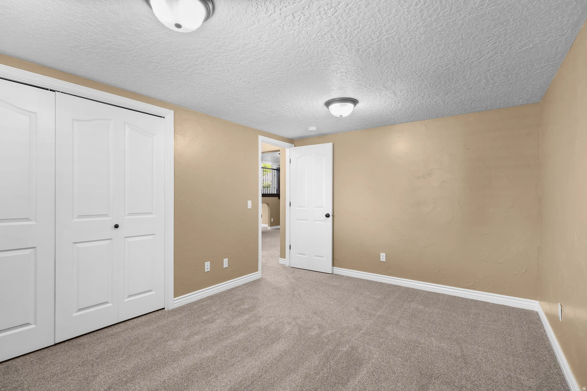 Carpeted room with neutral-toned walls, white baseboards, and a textured ceiling