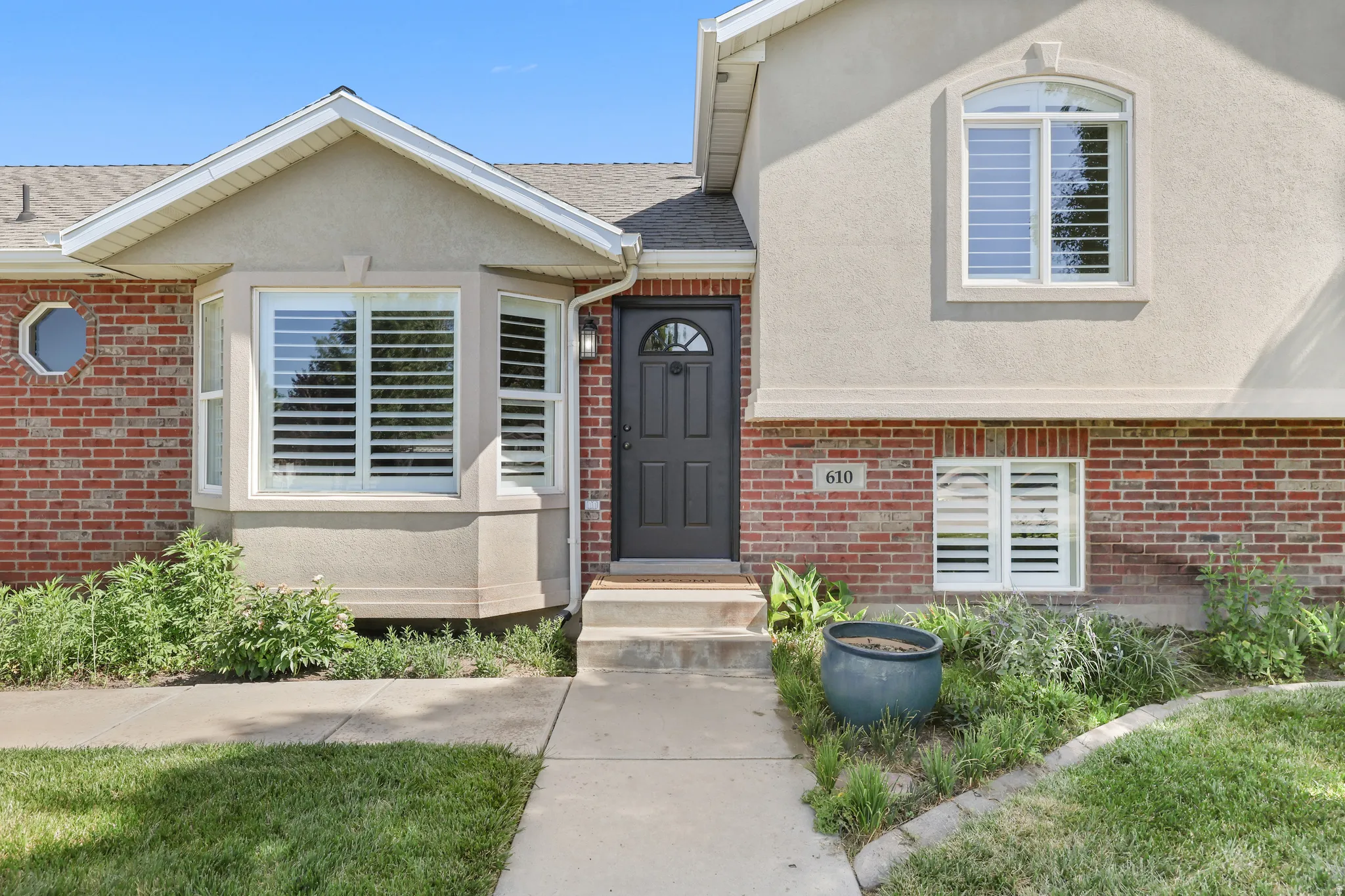 Exterior featuring red brick and stucco siding with a black entry door