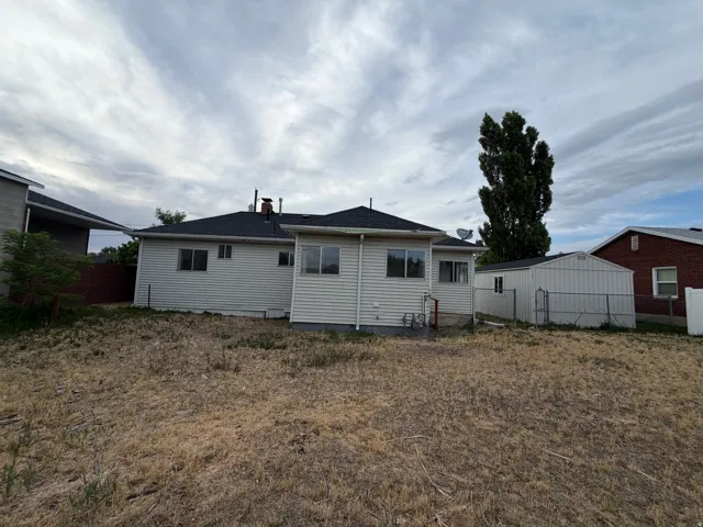 Rear exterior featuring light-colored horizontal siding, a dark shingle roof, and multiple windows