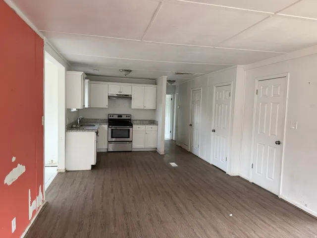 Kitchen area featuring white cabinetry, granite-style countertops, and a stainless steel oven/range