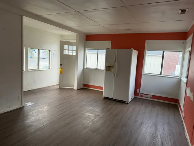 Open concept room featuring wood-finish flooring, multiple windows, a paneled ceiling, and an entry door with glass inserts