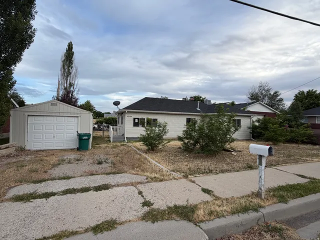 Property exterior featuring a detached garage with an overhead door, a concrete driveway, and a sidewalk