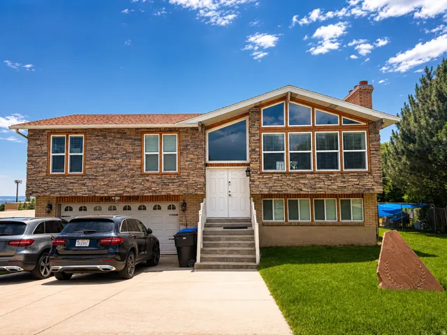 Stone facade residence featuring a two-car garage, prominent white double entry doors, an expansive upper-level window arrangement