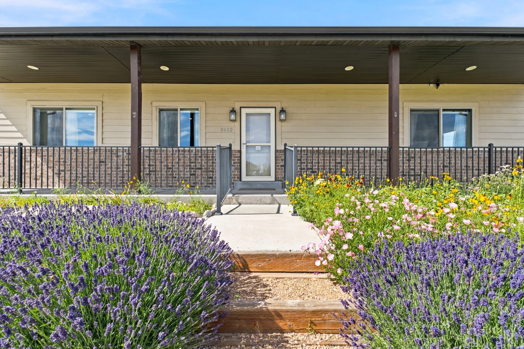 Covered front porch featuring a metal railing system, brick-look siding, and light-toned horizontal siding