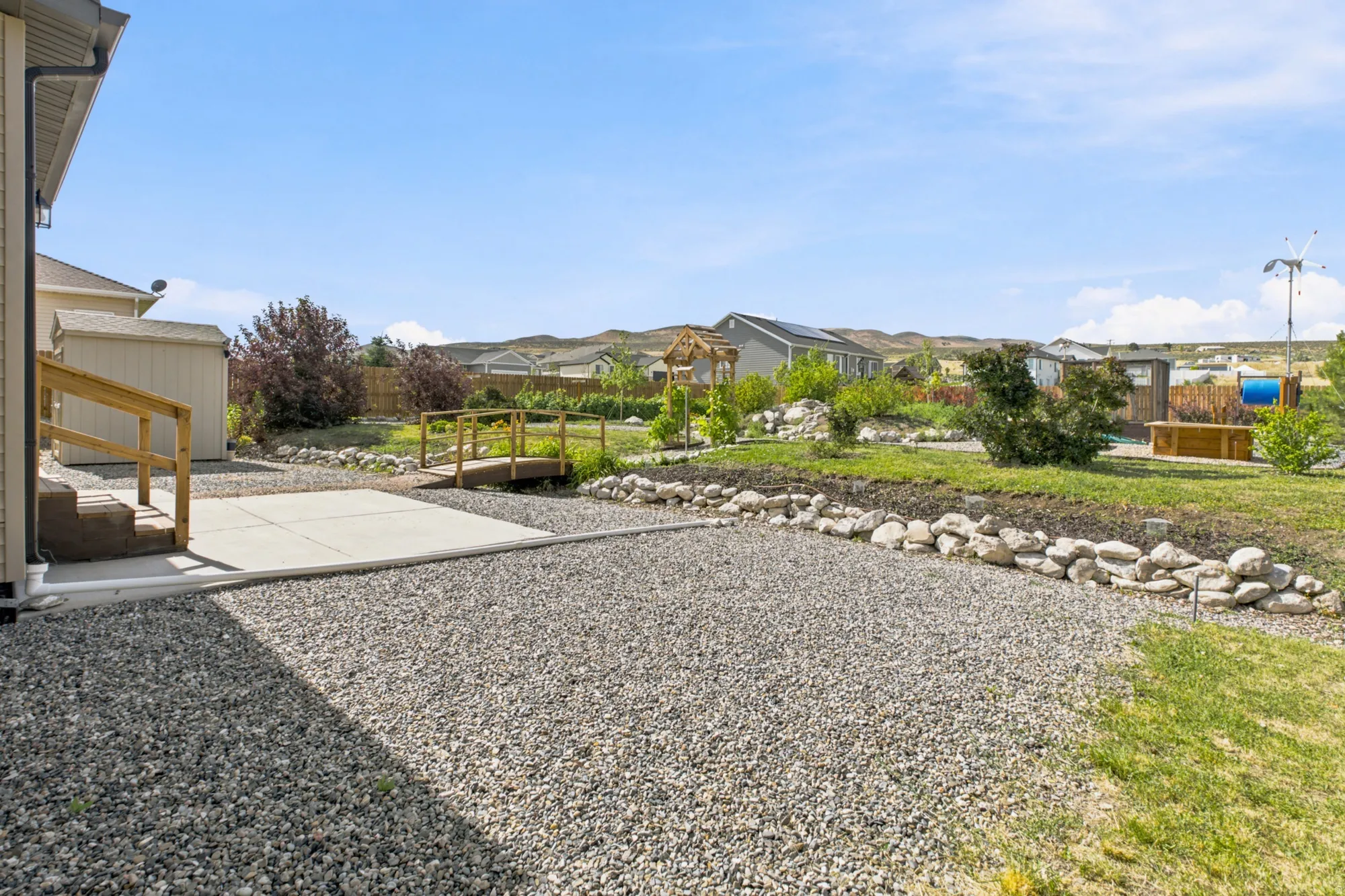 Expansive outdoor space featuring a concrete patio, gravel area, and a decorative bridge