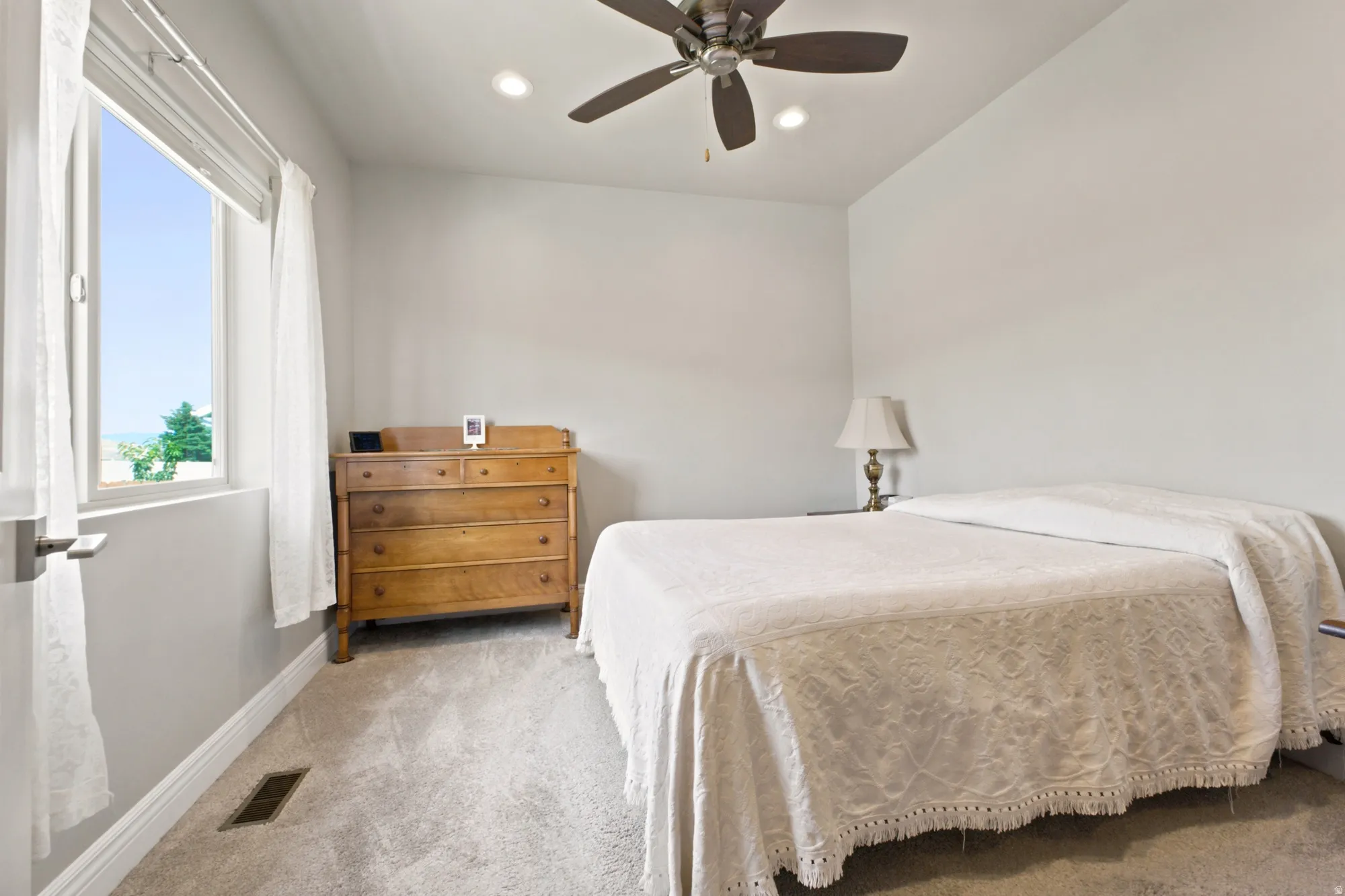 Carpeted interior space featuring a window, ceiling fan with integrated lighting, and recessed lighting
