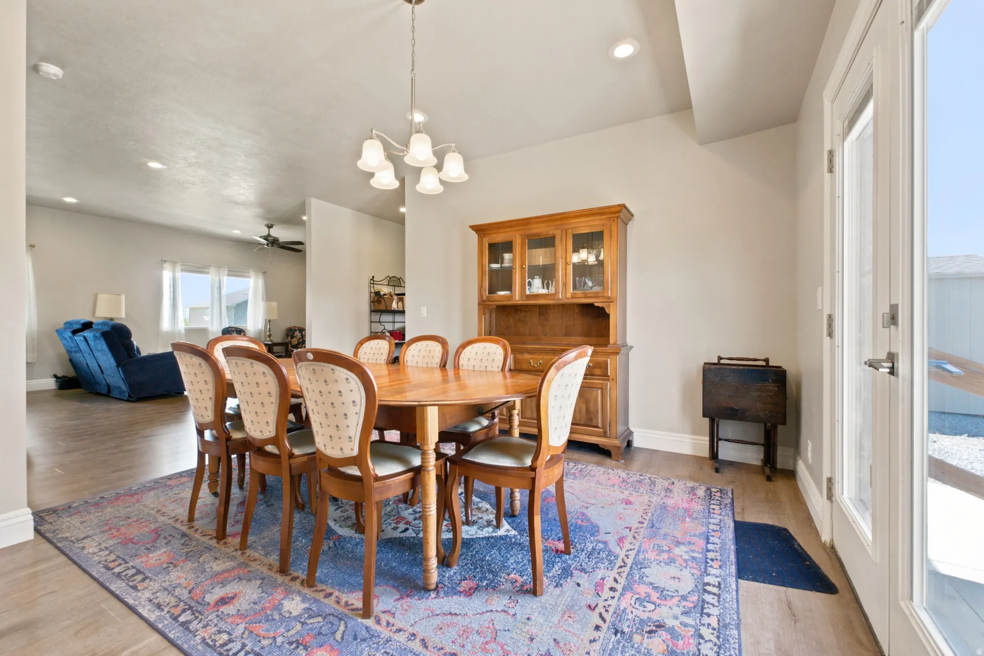 Inviting dining area featuring wood-finish flooring, a contemporary chandelier, recessed lighting, and a glass-paneled exterior door