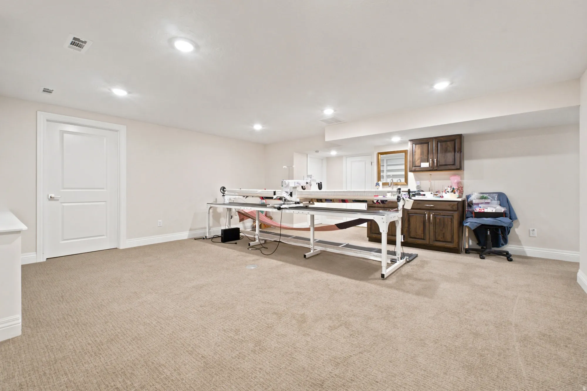 Family room with recessed lighting, light-toned carpeting, and a kitchenette with dark wood-finish doors and drawers