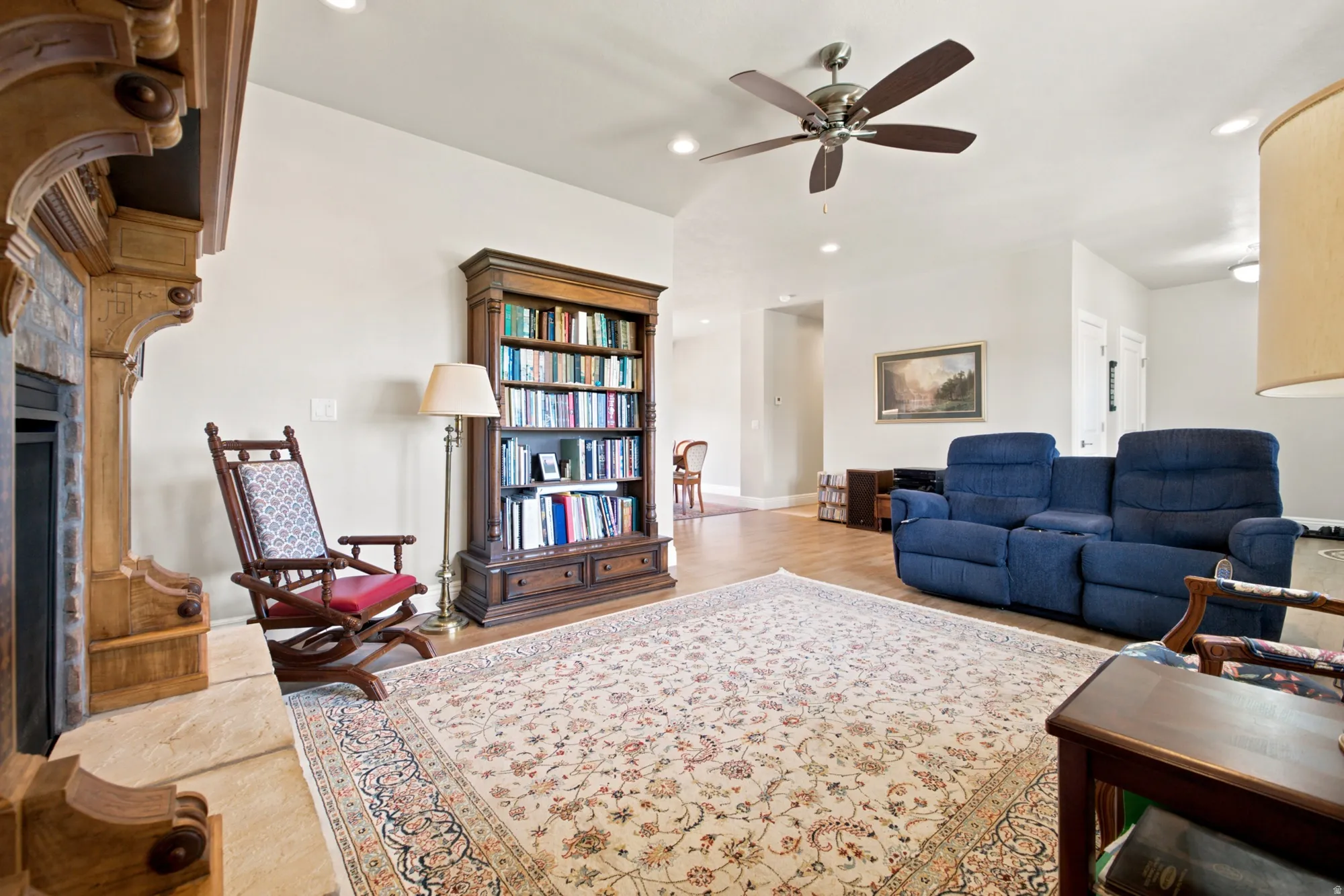 Spacious living area featuring a decorative area rug, light wood-finish flooring, and a ceiling fan
