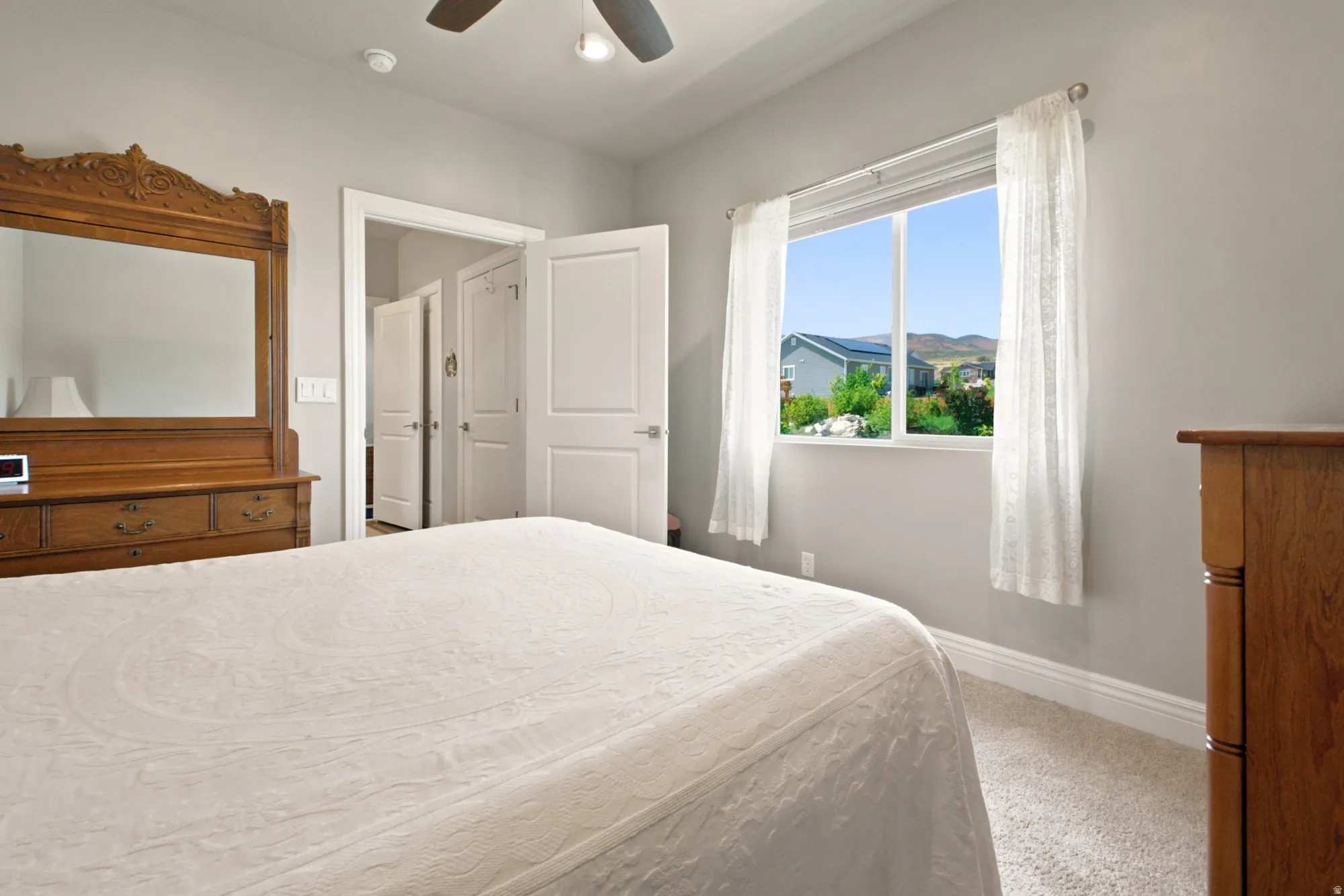 Carpeted bedroom featuring a ceiling fan, a window with a mountain backdrop, and a white interior door