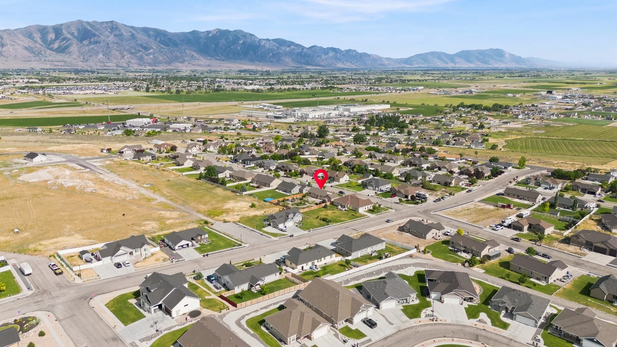 Expansive residential development featuring a mix of established homes and undeveloped lots, set against a backdrop of distant mountains