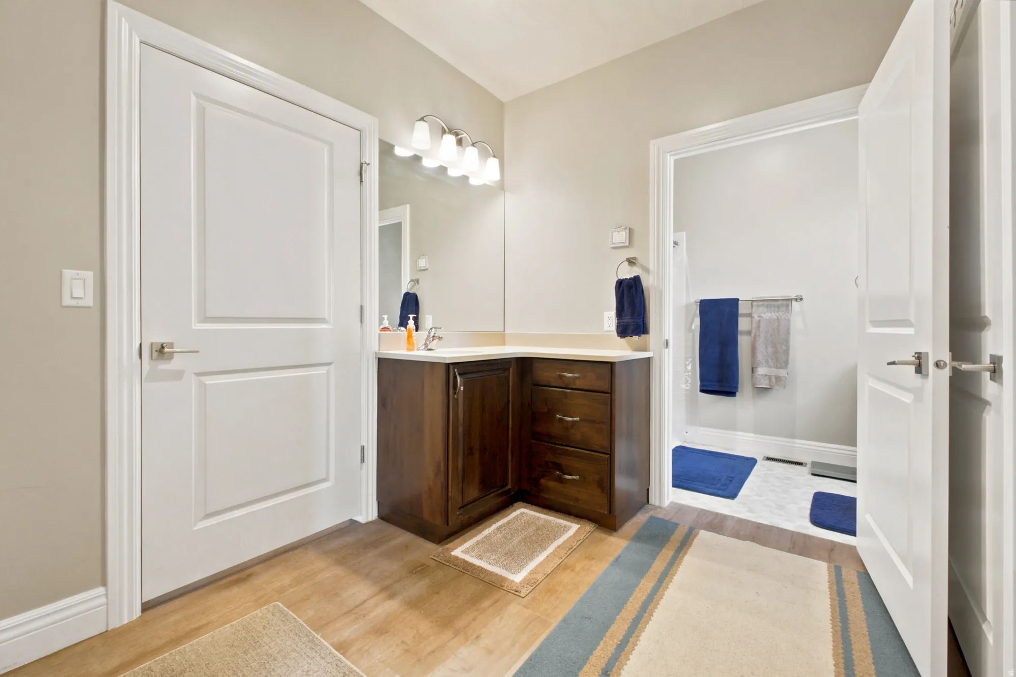 Bathroom featuring a corner wood-finish vanity with a light-colored countertop and a mirror above