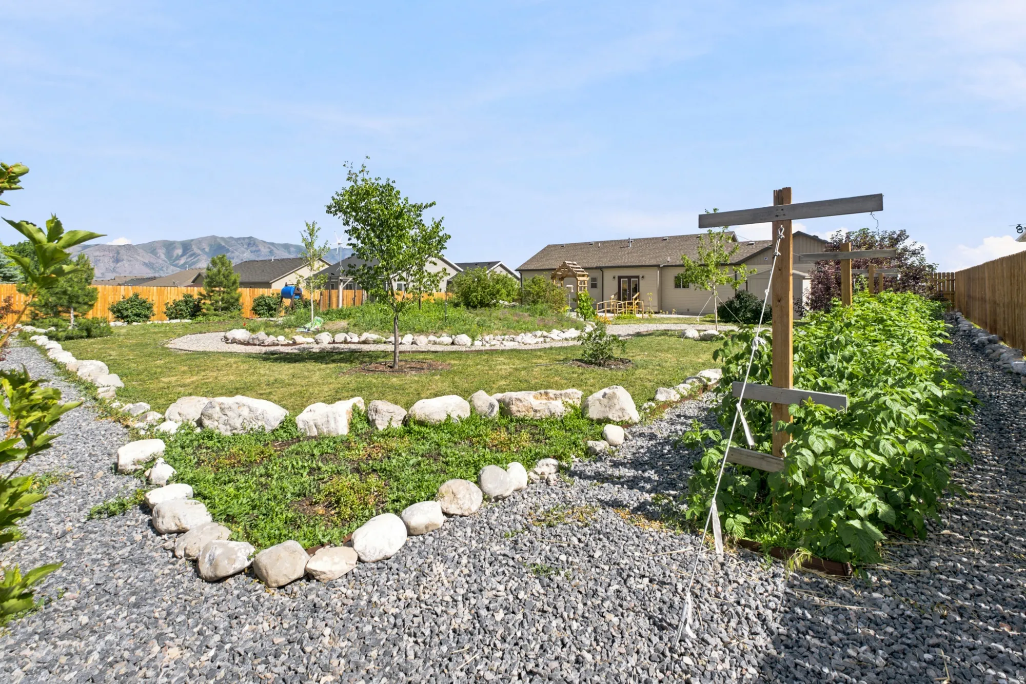 Expansive backyard featuring a lush lawn, gravel pathways, and a dedicated garden area with trellises