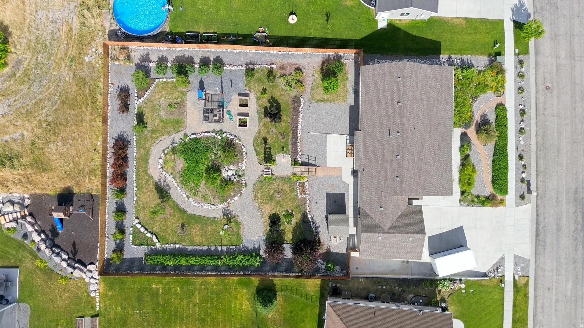 Extensive backyard landscaping featuring gravel pathways, circular garden beds, mature plantings, and a dedicated play area