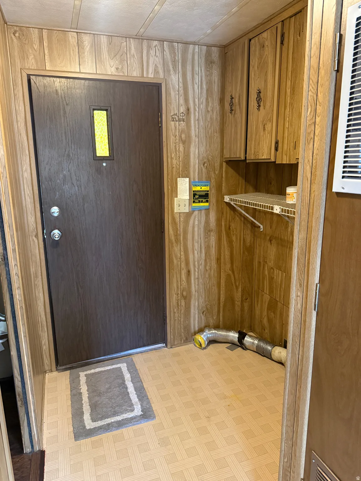 Entryway featuring wood-look wall paneling and patterned vinyl flooring