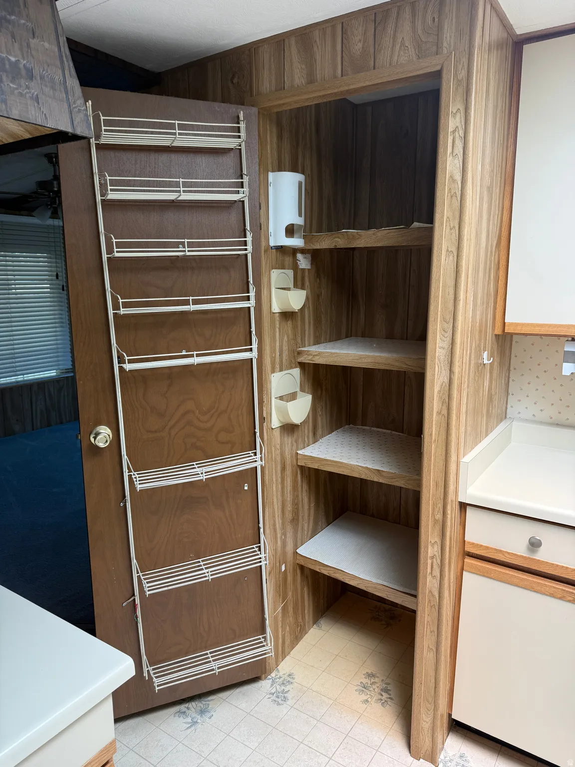 Integrated pantry storage with wood-finish paneling, fixed shelving, and a door-mounted rack system