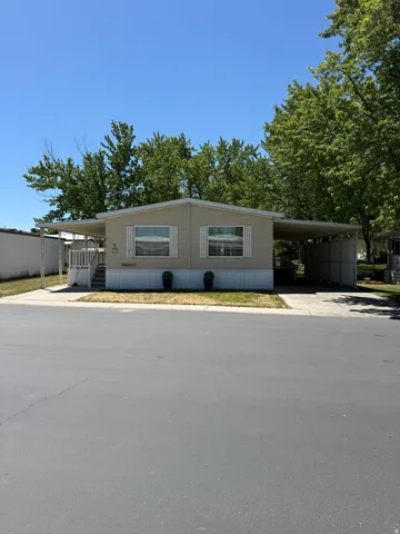 Single-story manufactured home featuring a neutral-toned exterior, white window shutters, and a covered porch entry