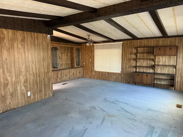 Spacious interior featuring wood-panel walls, exposed ceiling beams, and built-in cabinetry