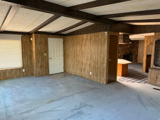 Spacious interior featuring wood-finish wall paneling, a white paneled door, and light blue carpeting