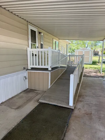 Covered entry with vinyl siding and a wood-finish ramp