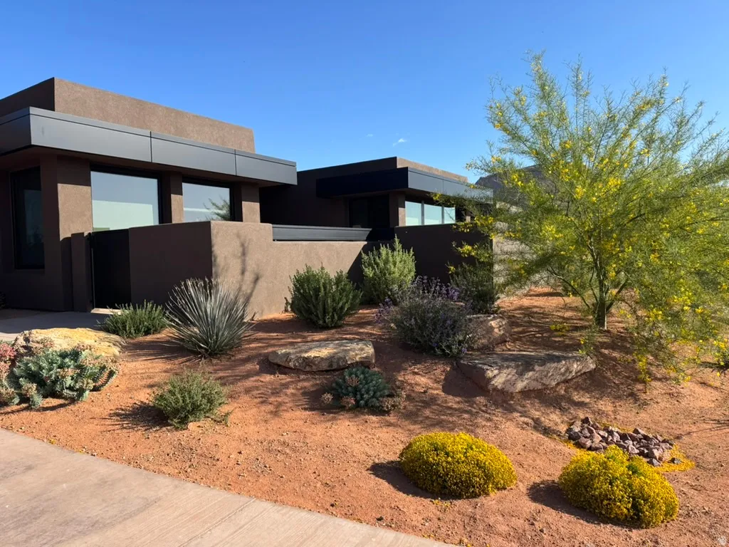 Contemporary exterior featuring stucco siding, dark trim accents, expansive windows, and a Xeriscape landscape design
