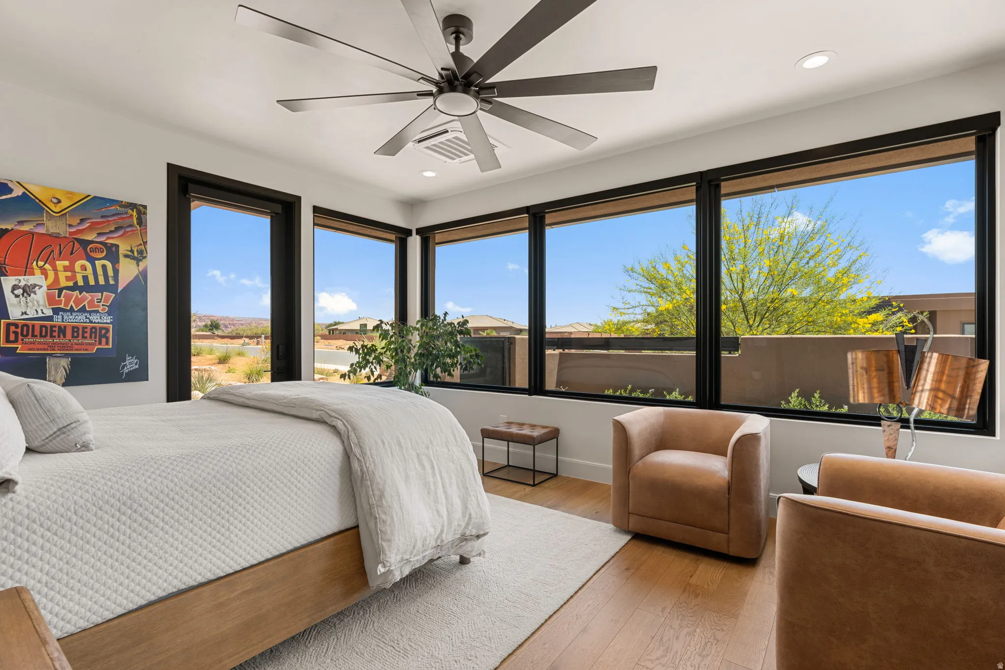 Room featuring a multi-paneled window wall with dark framing and a large ceiling fan with private entrance.