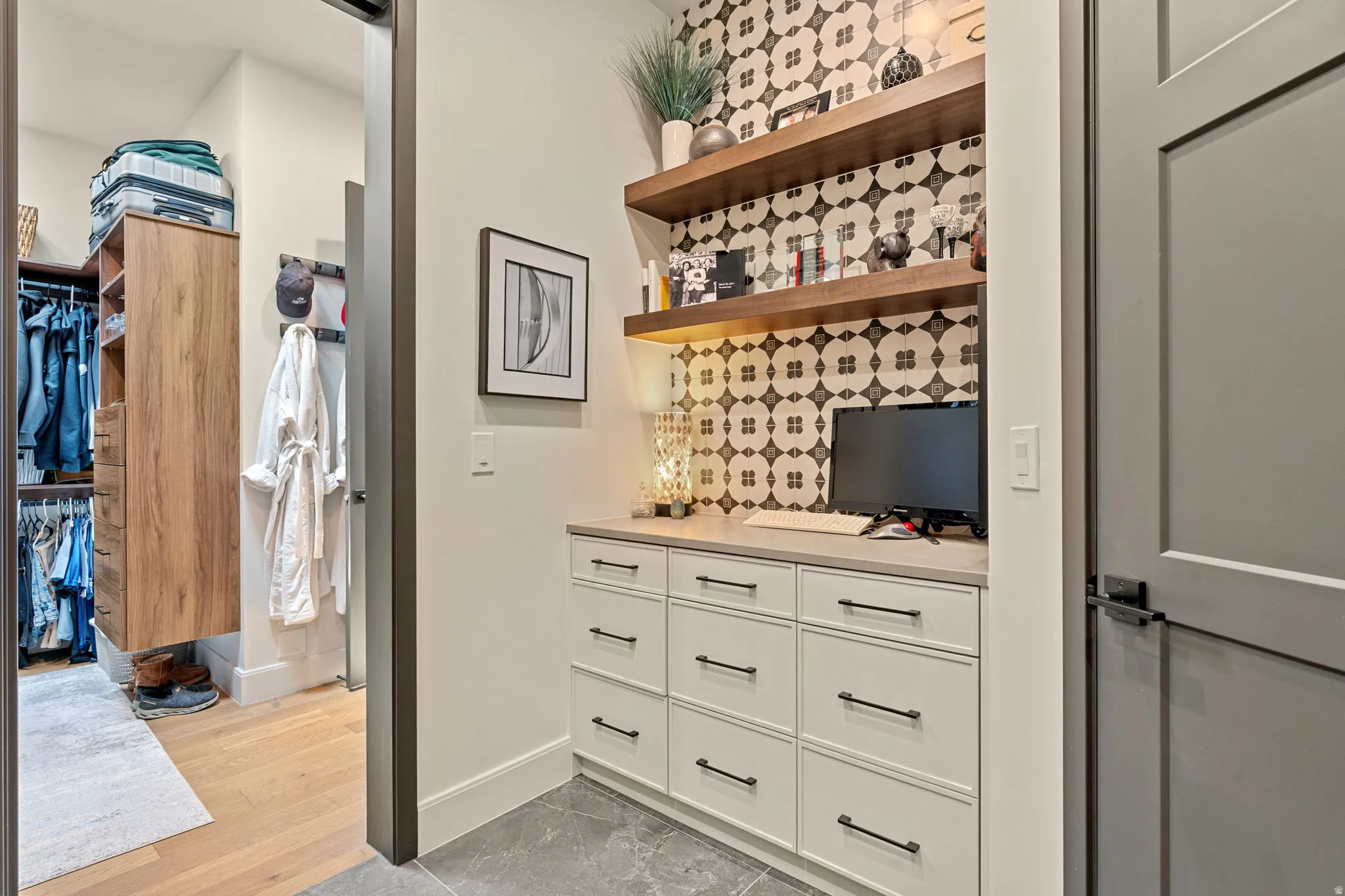 Laundry room with access to owner's suite closet.  Area features a patterned tile backsplash, floating wood shelves, and recessed lighting