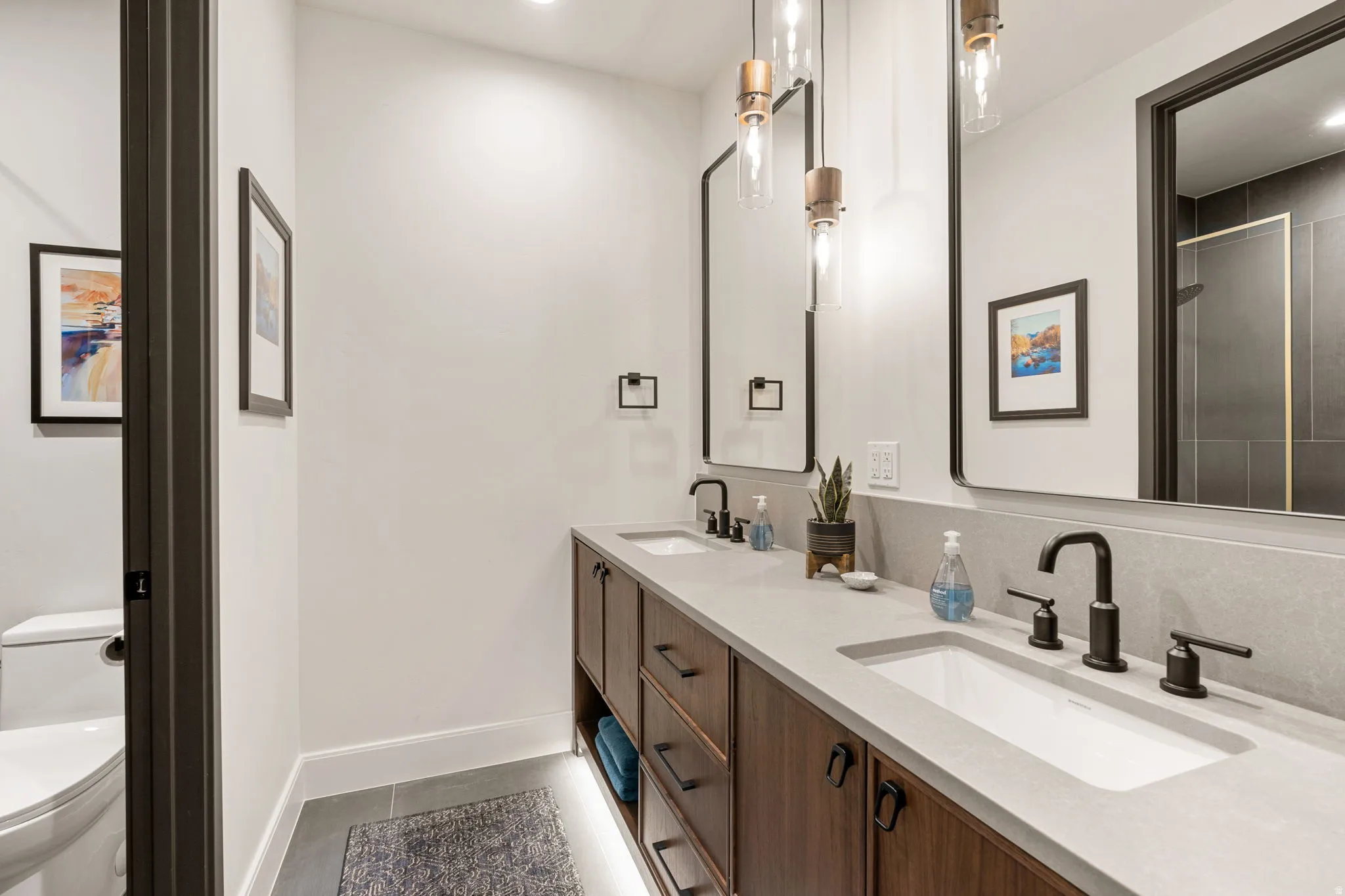 Casita bathroom featuring a dual-sink vanity with wood cabinetry, light-toned countertops, and matte black hardware