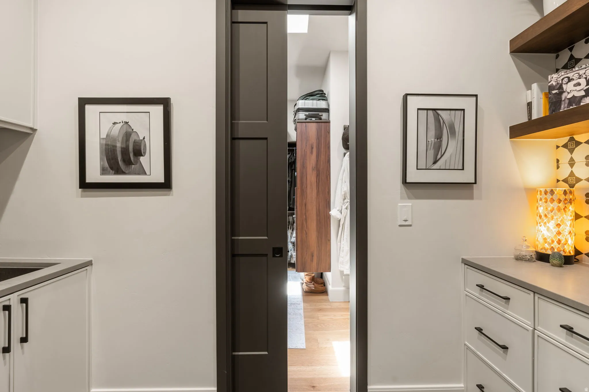 Pocket door entry to a secondary owner's suite closet featuring wood-finish flooring