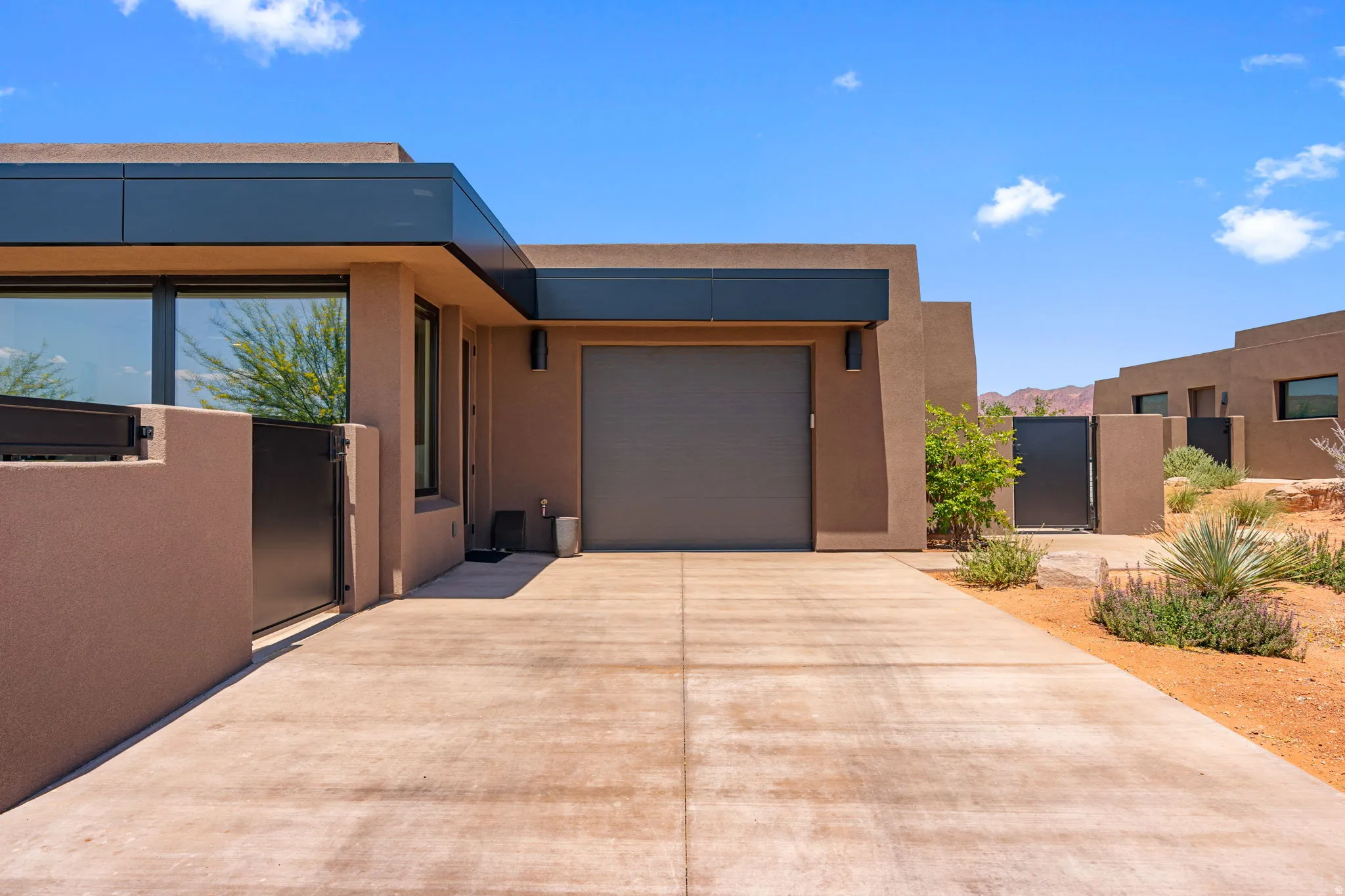 North driveway of contemporary style home featuring a flat roofline and stucco finish