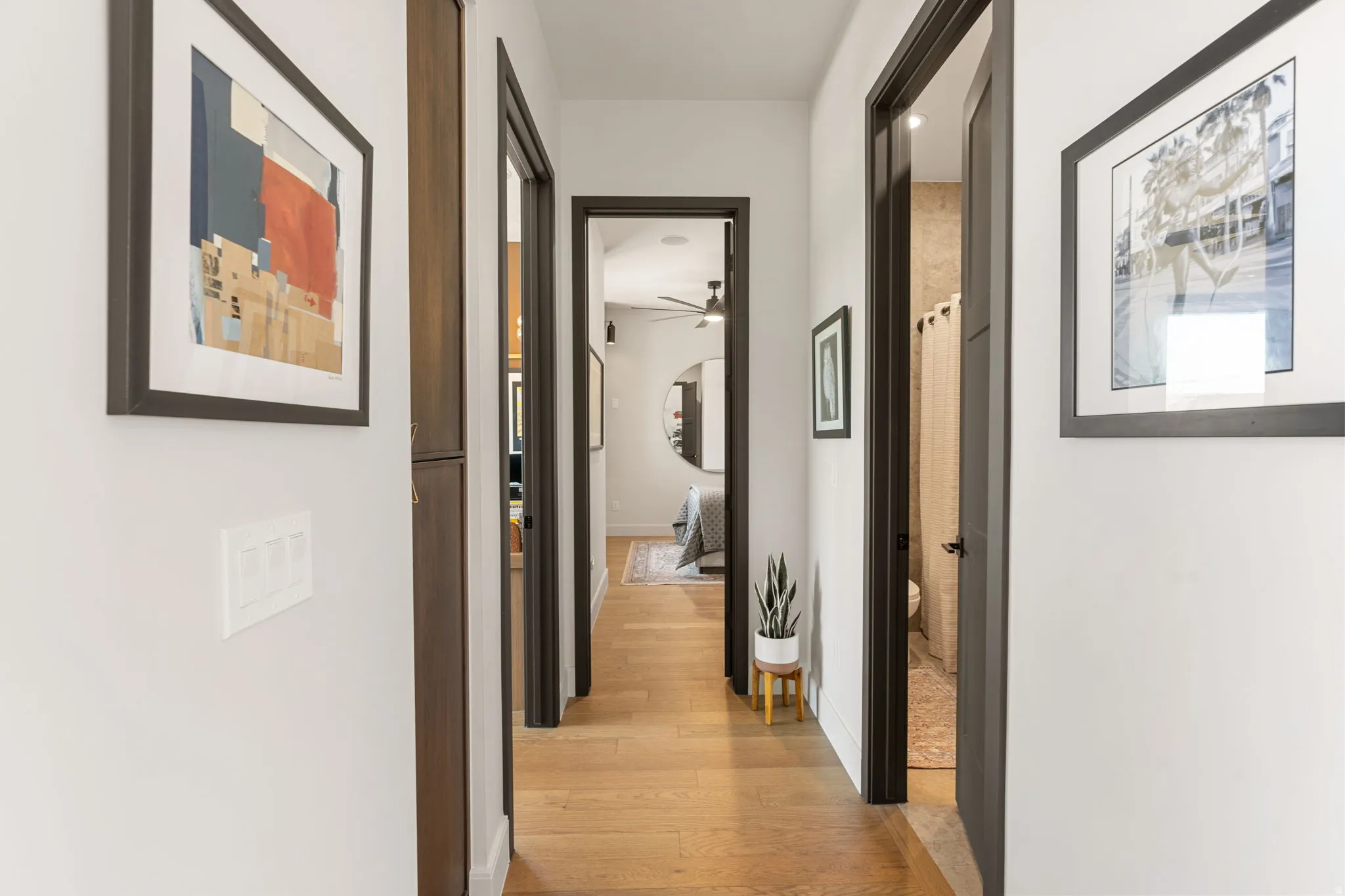 Hallway featuring hardwood flooring, white walls, and dark-trimmed doorways