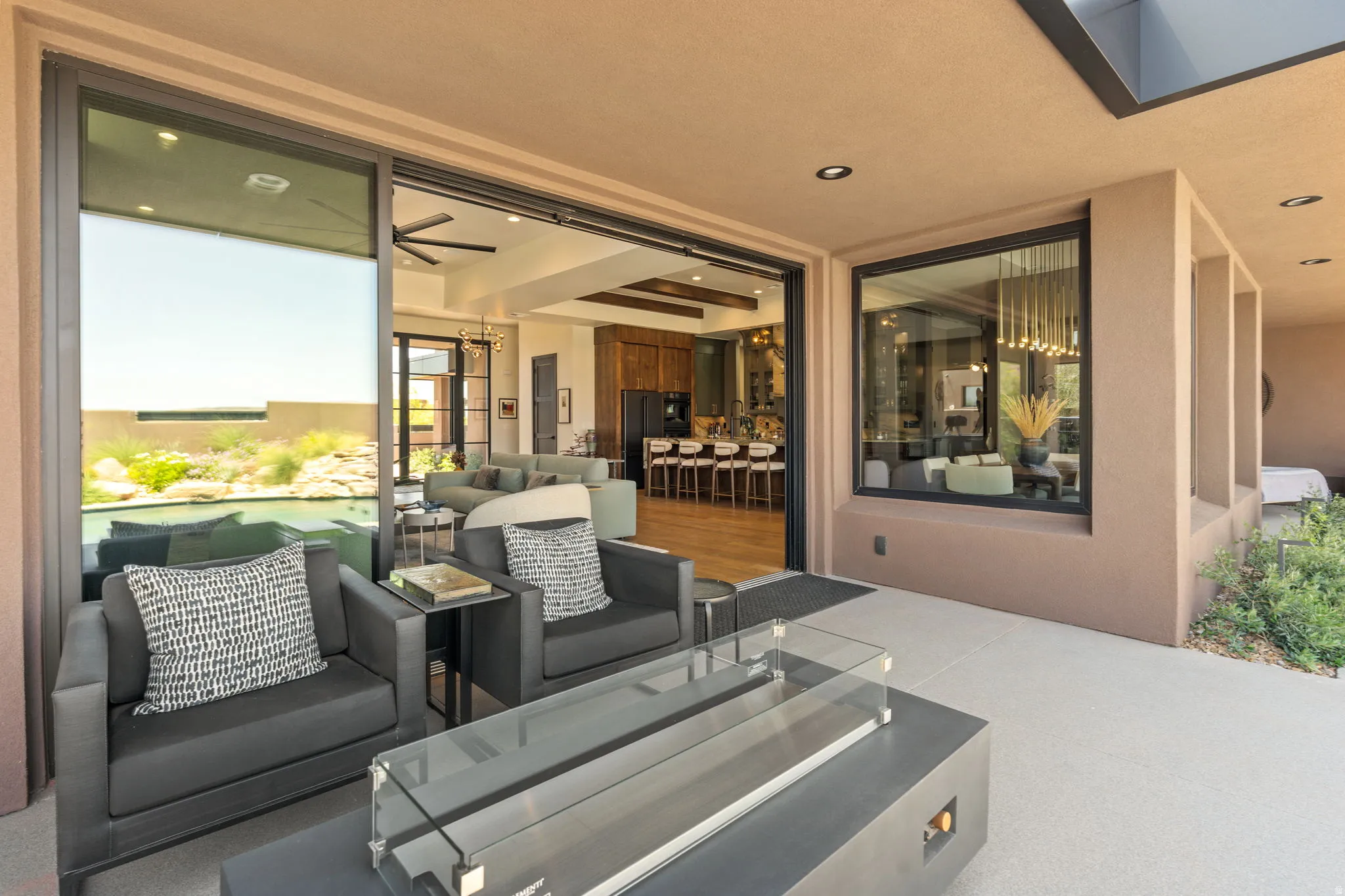 Expansive outdoor patio featuring a modern fire pit with direct access to interior living spaces via large sliding glass doors