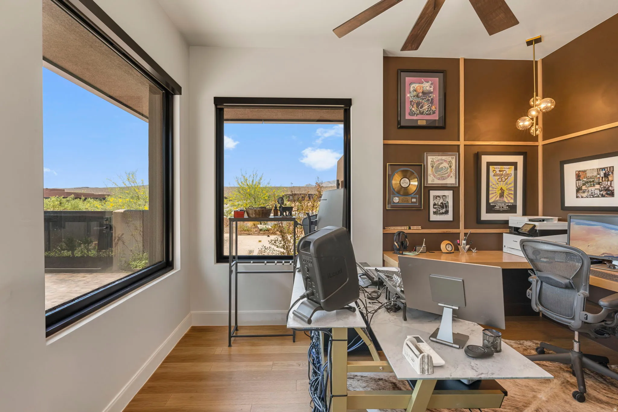 Room featuring expansive windows with shades, hardwood flooring, a wood-paneled ceiling fan, and an accent wall with dimensional wood trim