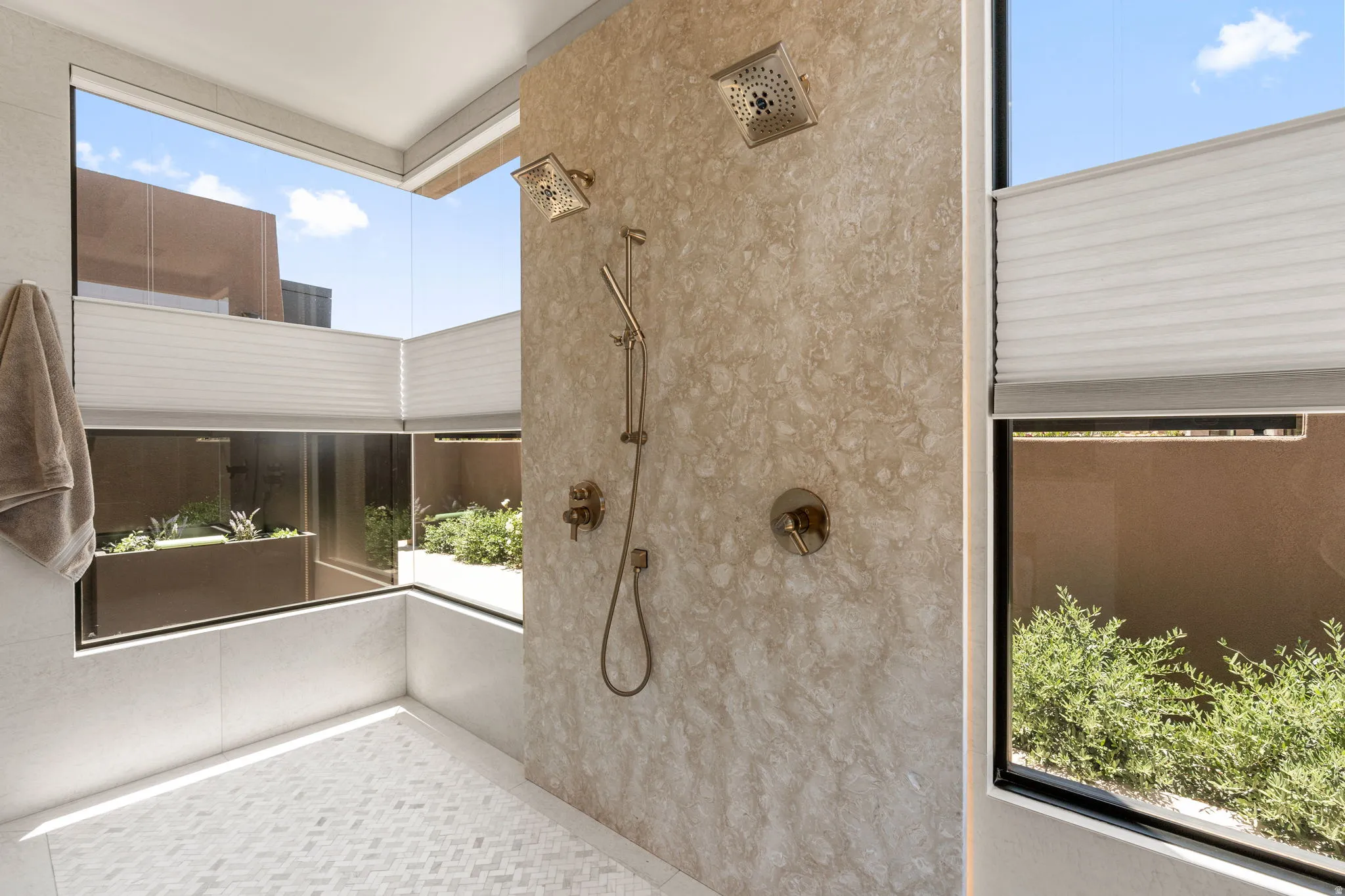 Shower with a mosaic tile floor, stone slab wall, and dual shower heads