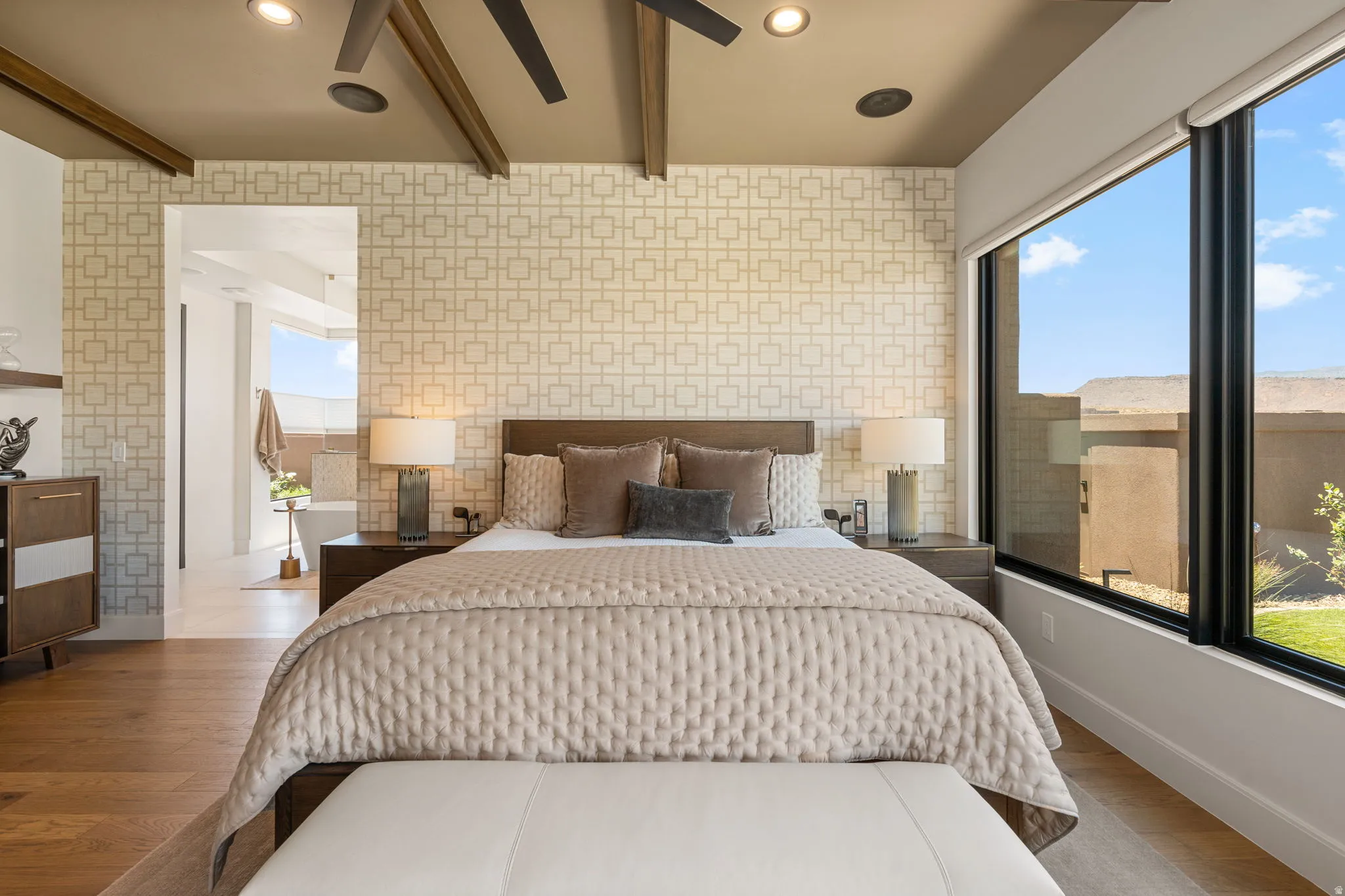 Owner's Suite featuring an accent wall with geometric pattern, hardwood flooring, a contemporary ceiling fan, recessed lighting, and expansive windows