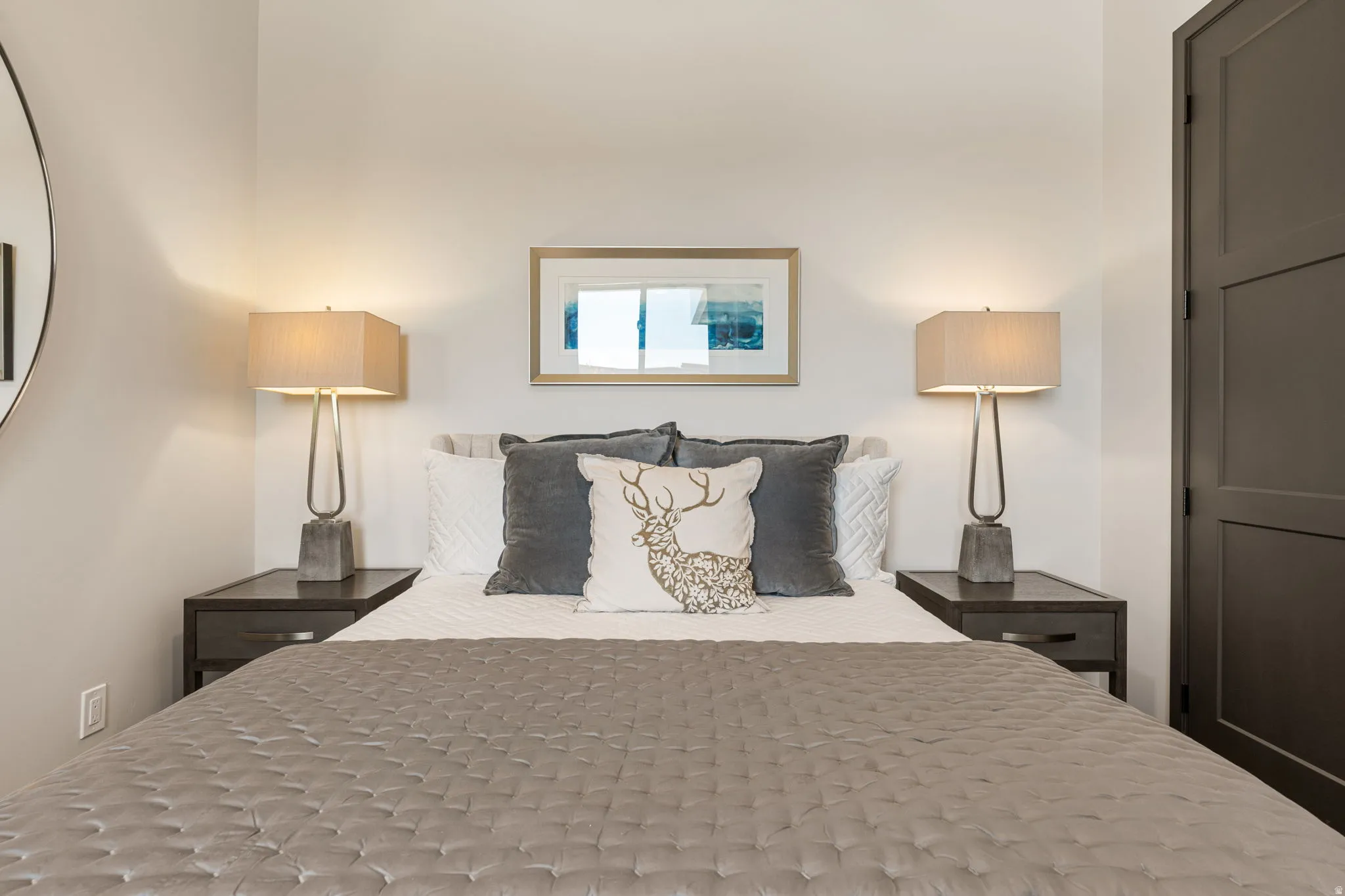 Third bedroom with neutral wall paint, framed art, and dark wood-finish nightstands with integrated drawers