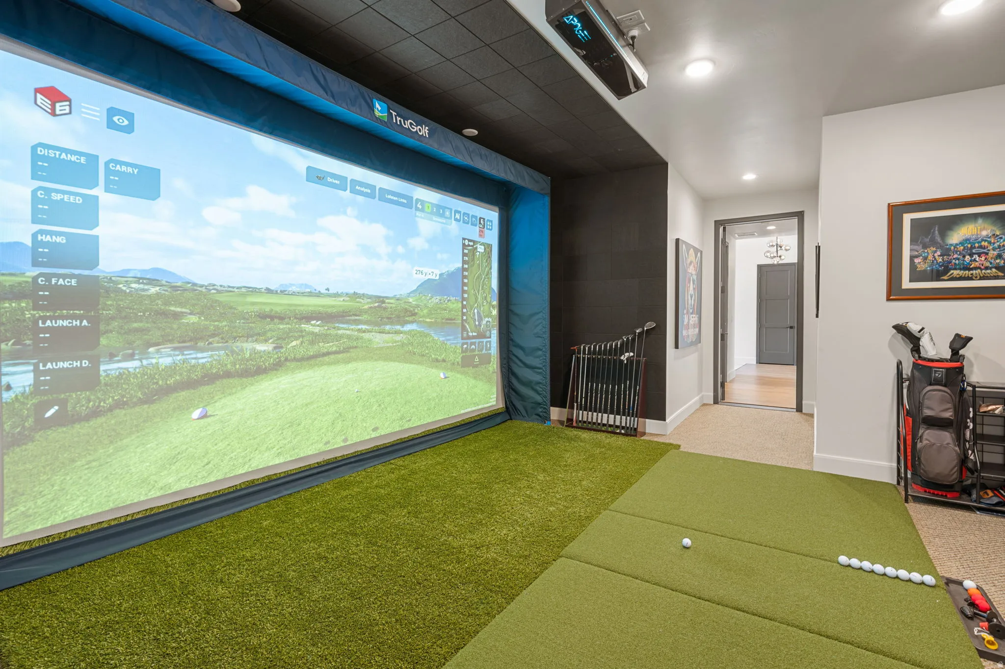 Dedicated golf simulator area featuring a large projection screen and artificial turf flooring