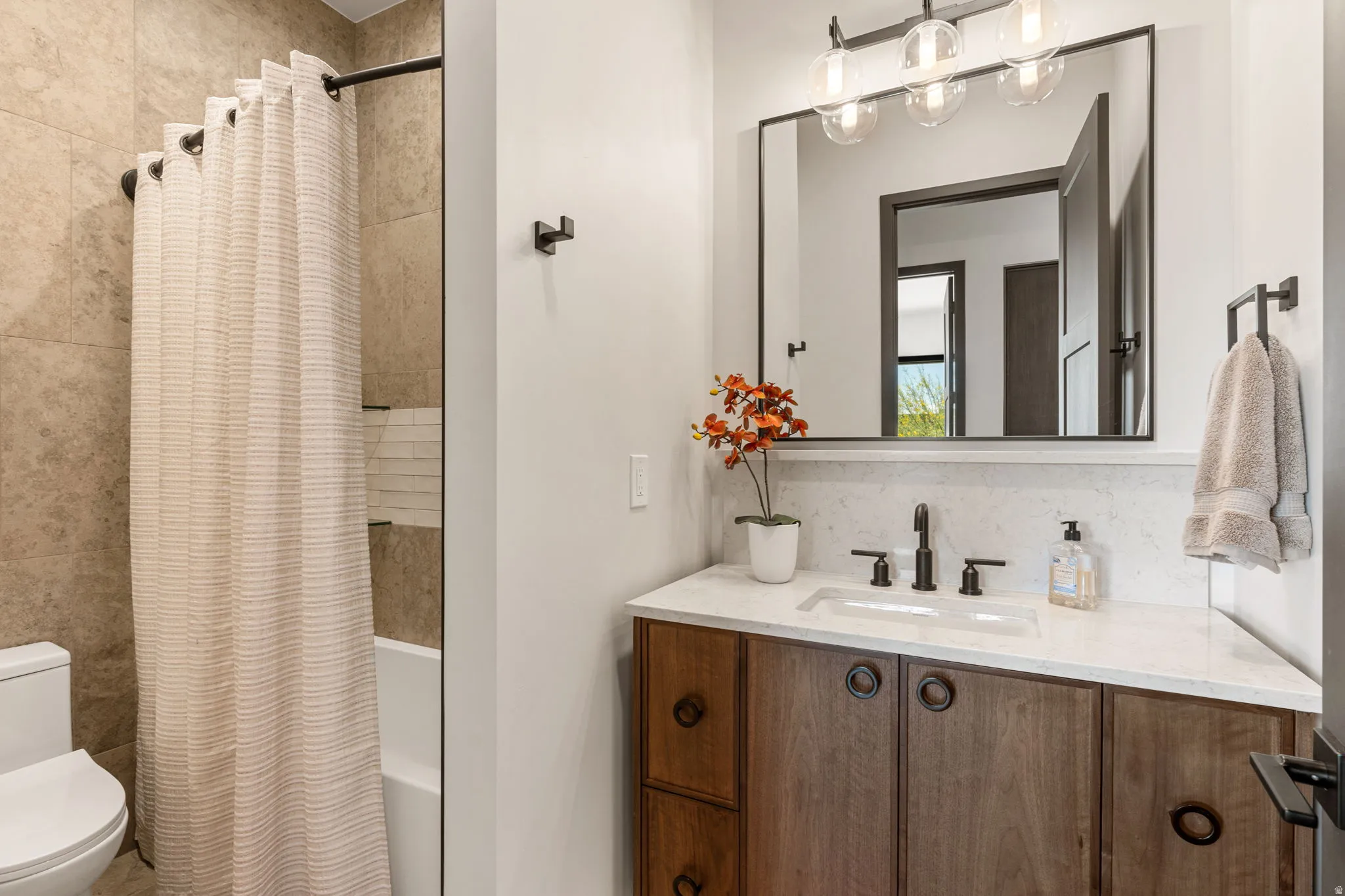 Bathroom featuring a wood vanity with a white countertop, an integrated sink, and matte black fixtures
