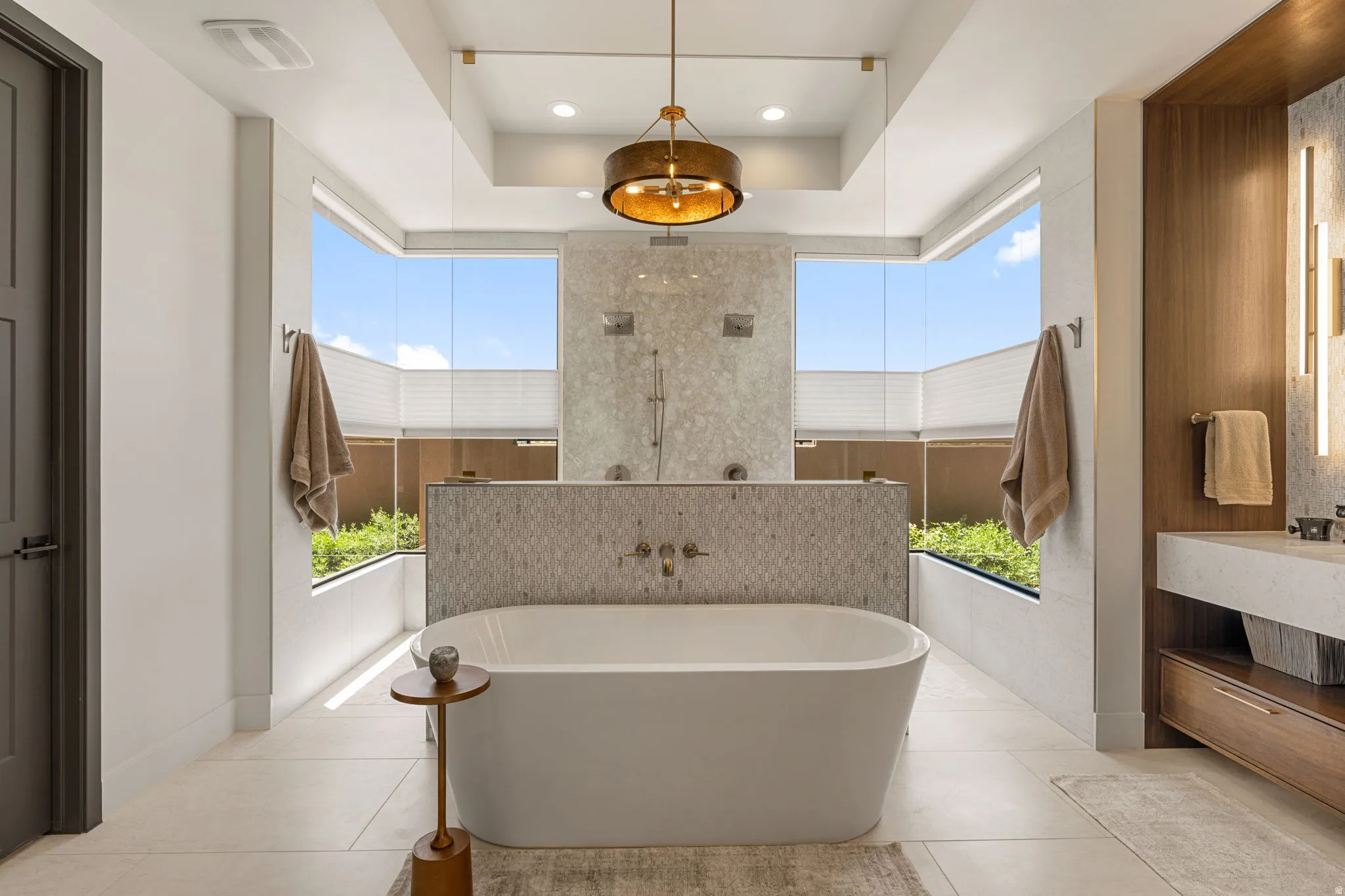 Contemporary bathroom featuring a freestanding soaking tub, a large walk-in shower with dual showerheads, stone slab Shower wall, tile accents, and expansive windows