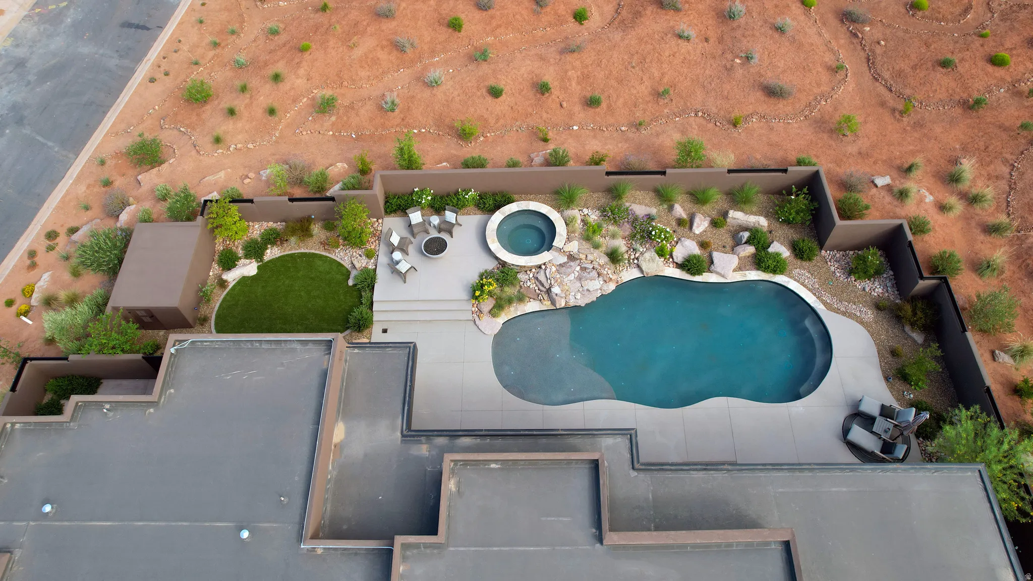 Curved swimming pool with integrated spa and surrounding concrete patio