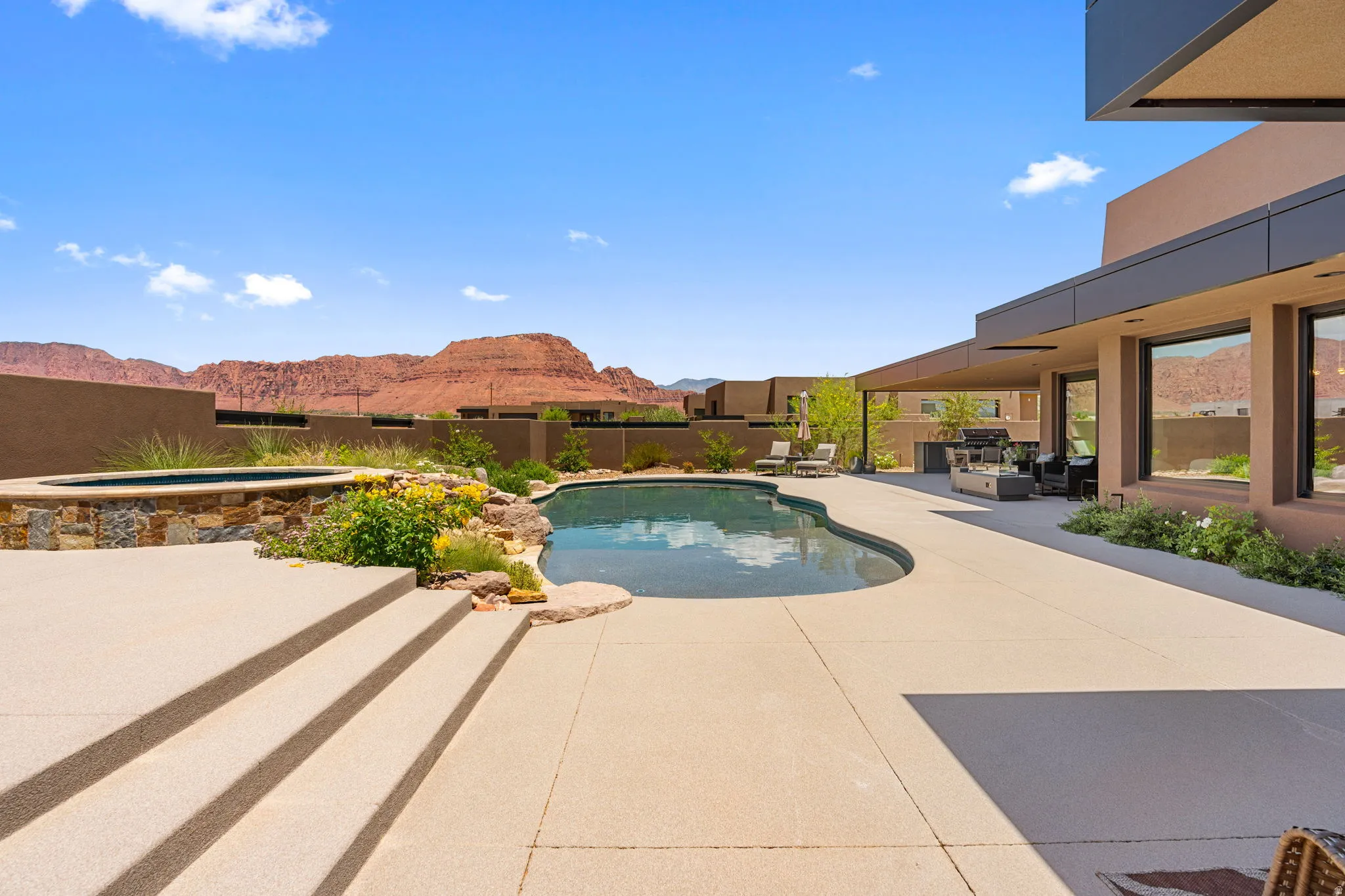 Contemporary exterior with an expansive patio featuring a curvilinear swimming pool and a stone-clad spa