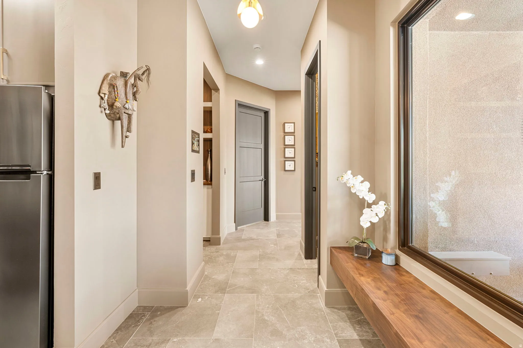 Hallway featuring large format tile flooring, a dark wood floating bench