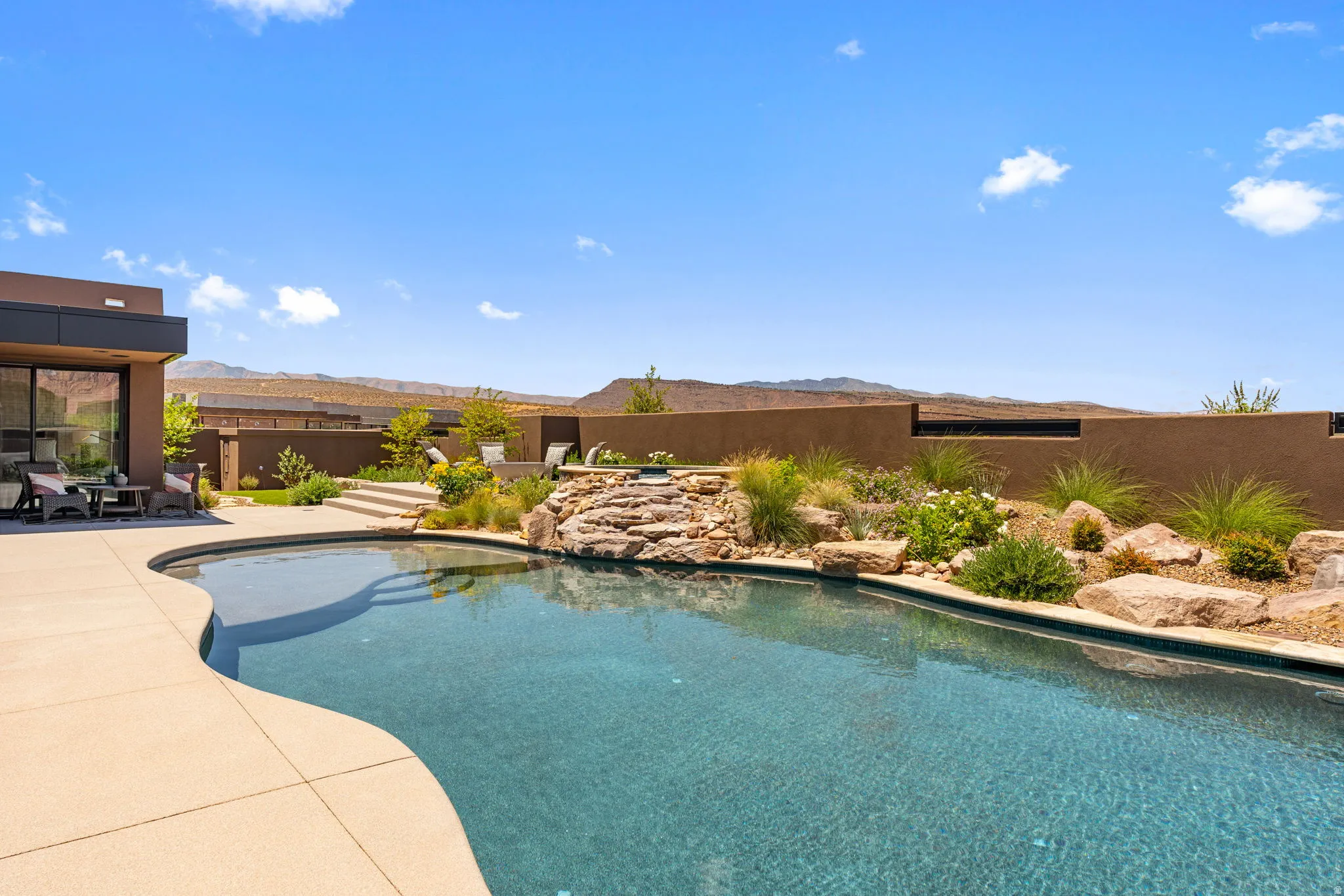 Freeform swimming pool with integrated spa and rock waterfall feature