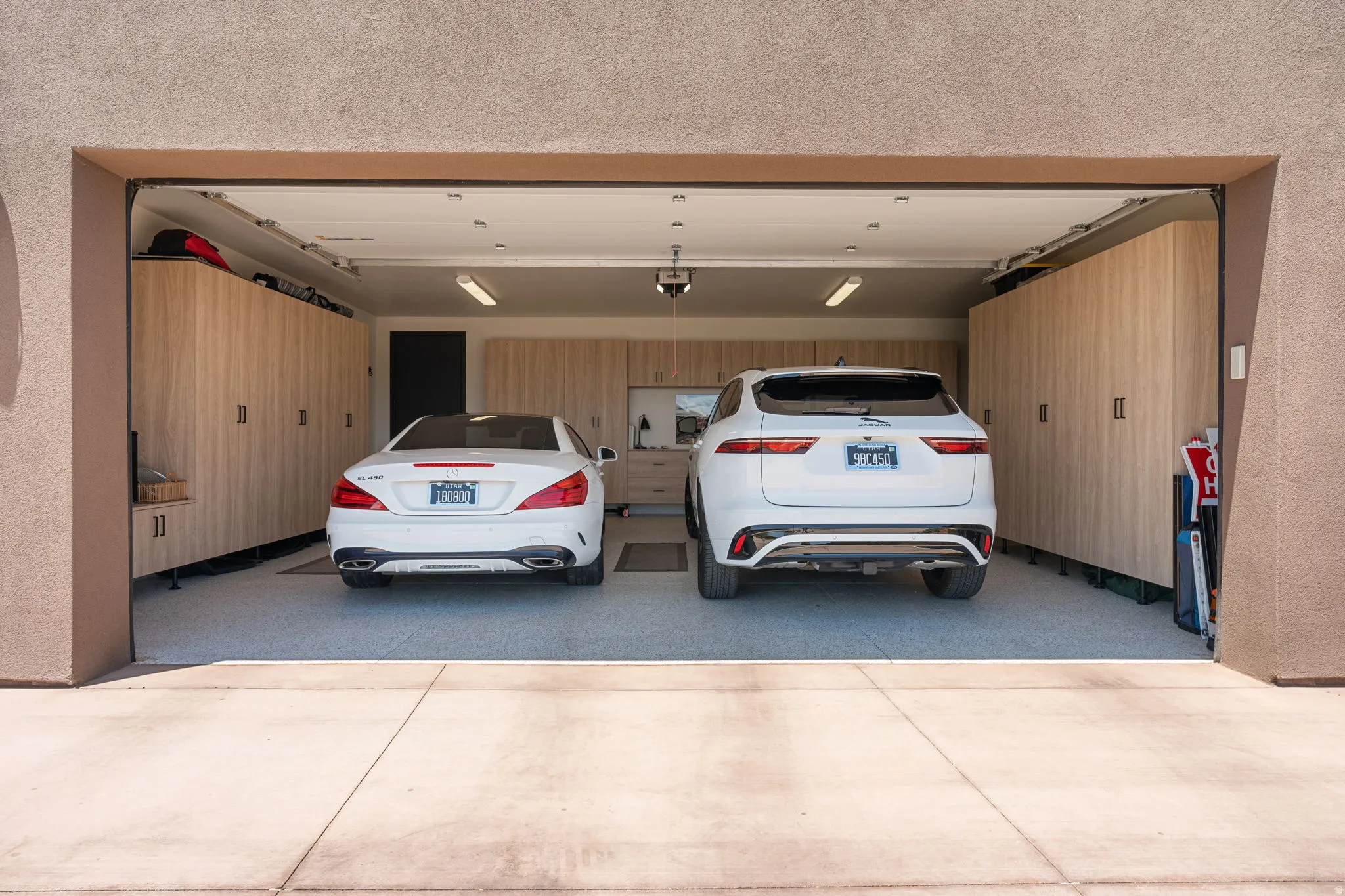 Two-car garage featuring extensive custom cabinetry, an epoxy-coated floor, and overhead fluorescent lighting