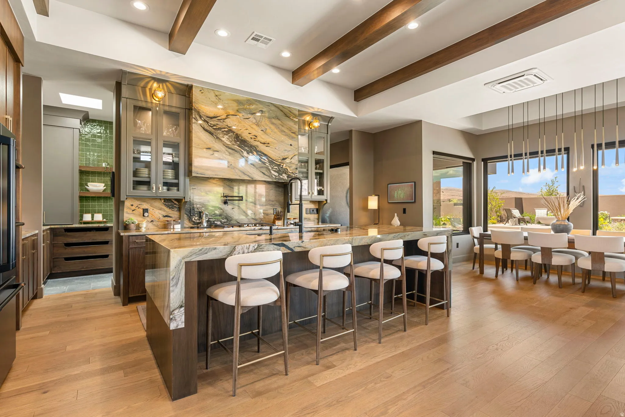 Gourmet kitchen with a waterfall edge island, custom cabinetry, full-height slab backsplash, and hardwood flooring