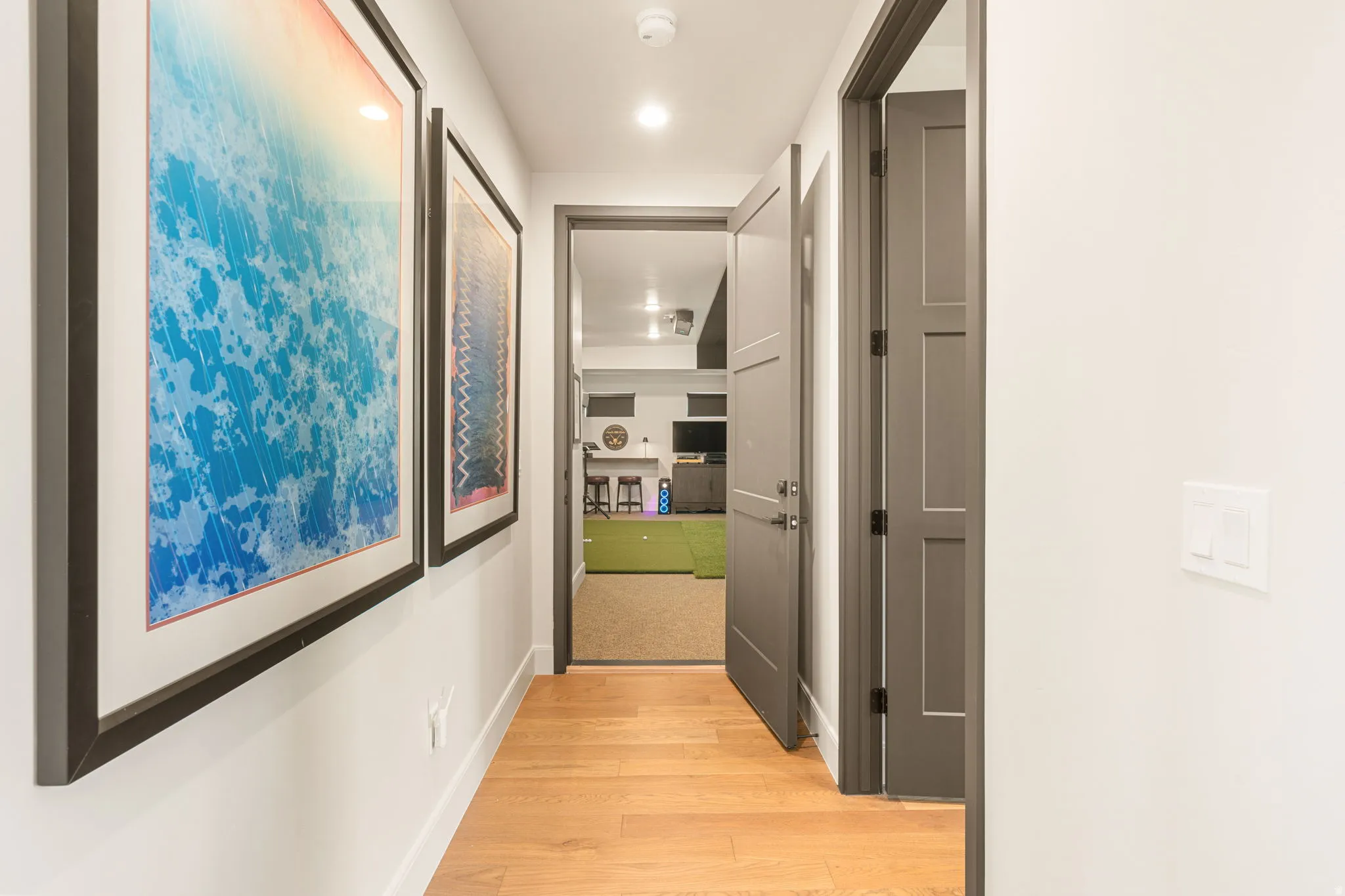 Hallway featuring wood-finish flooring, recessed lighting, and art wall